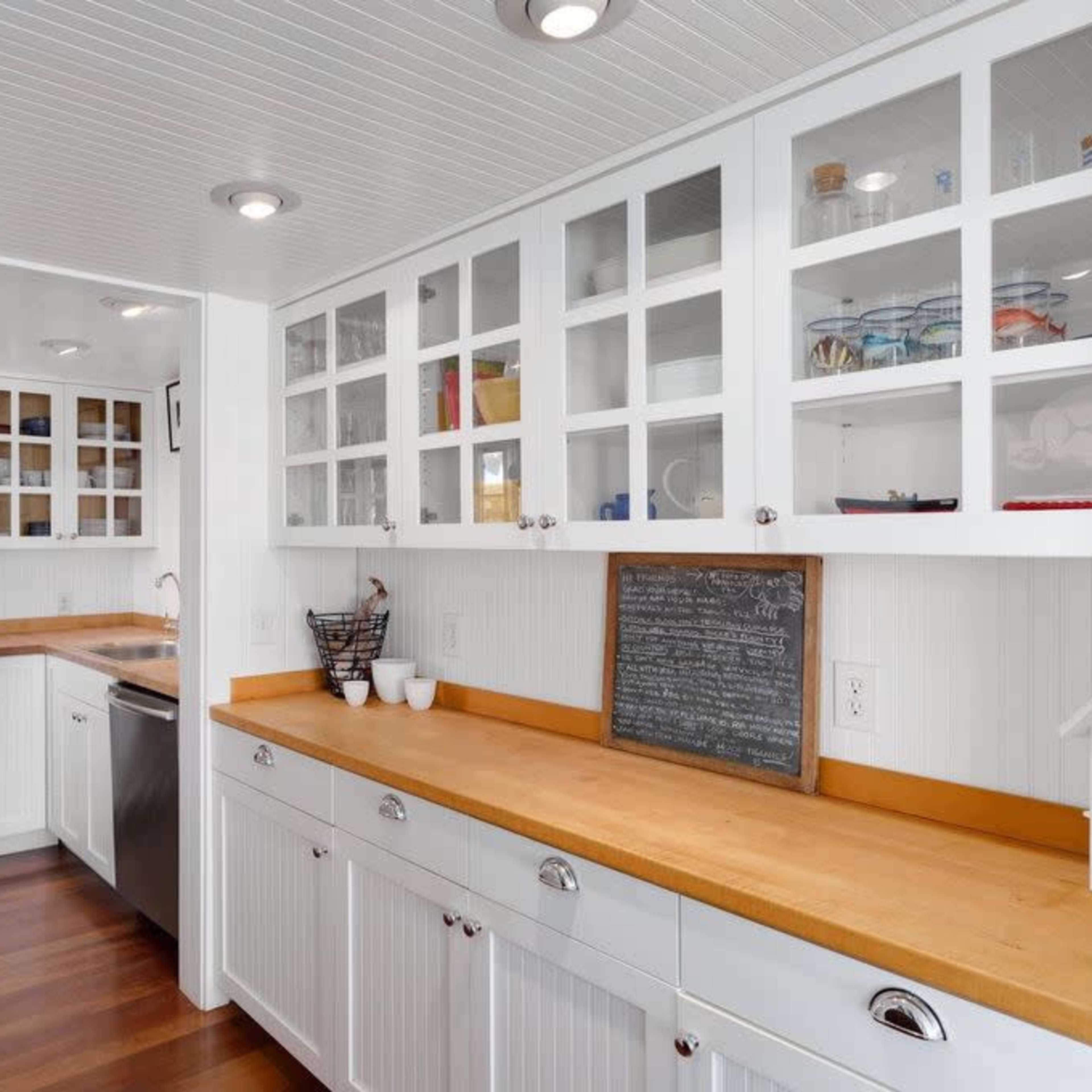 A modern kitchen with white cabinetry, stainless steel appliances, and wooden countertops.