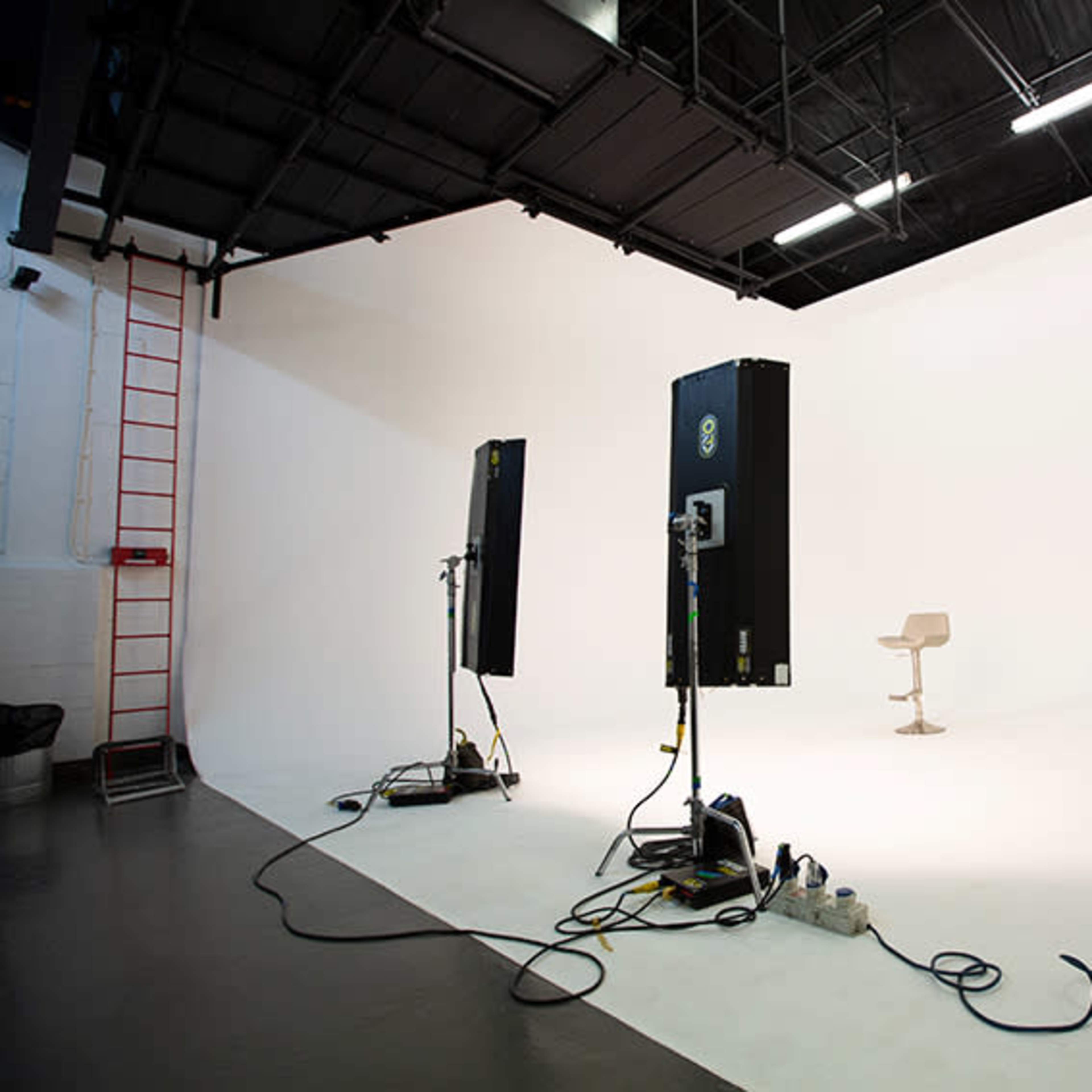 A minimalist photography studio with two large lights positioned on either side of a single chair against a white backdrop.