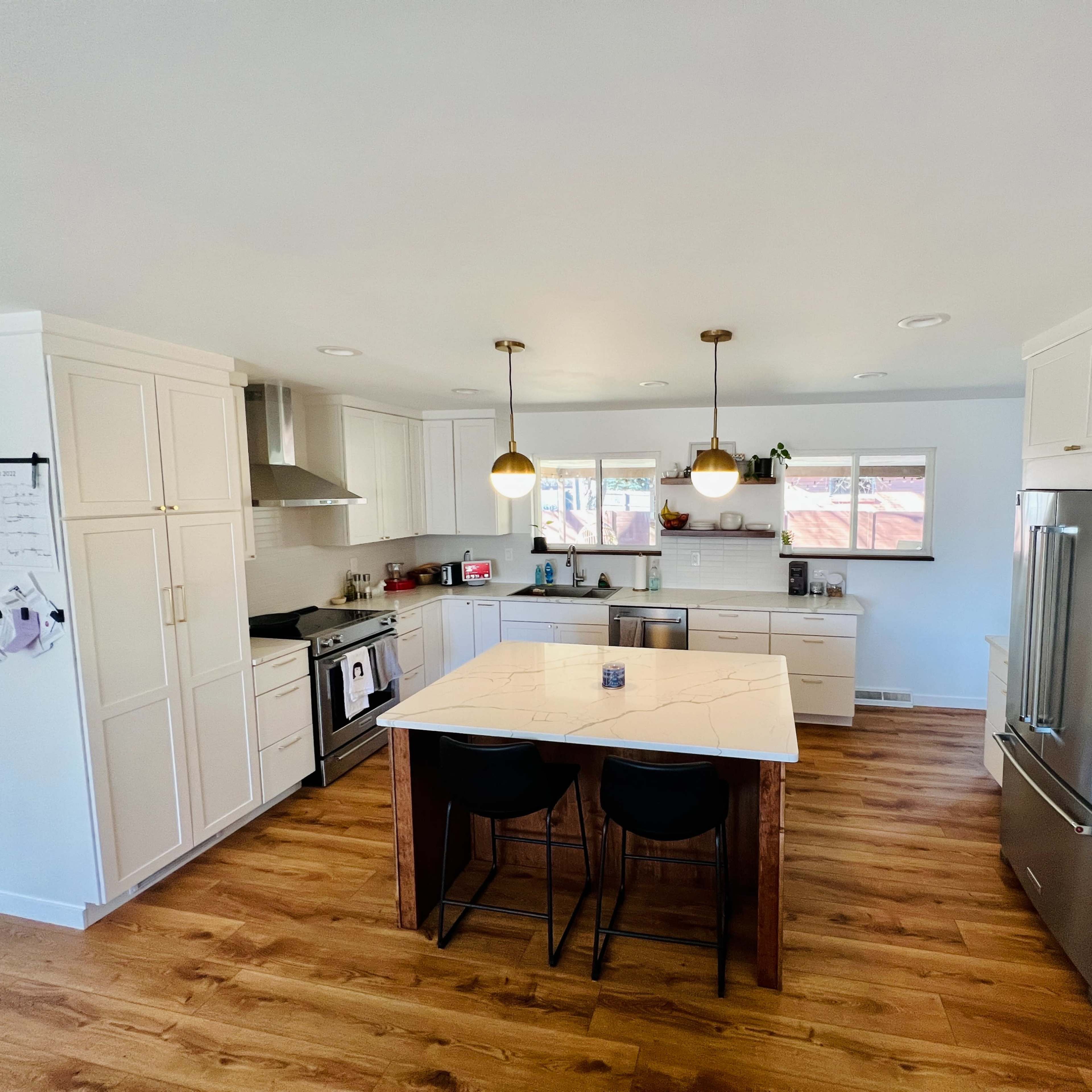 A modern kitchen features white cabinets, a large island with a marble countertop, and stainless steel appliances.