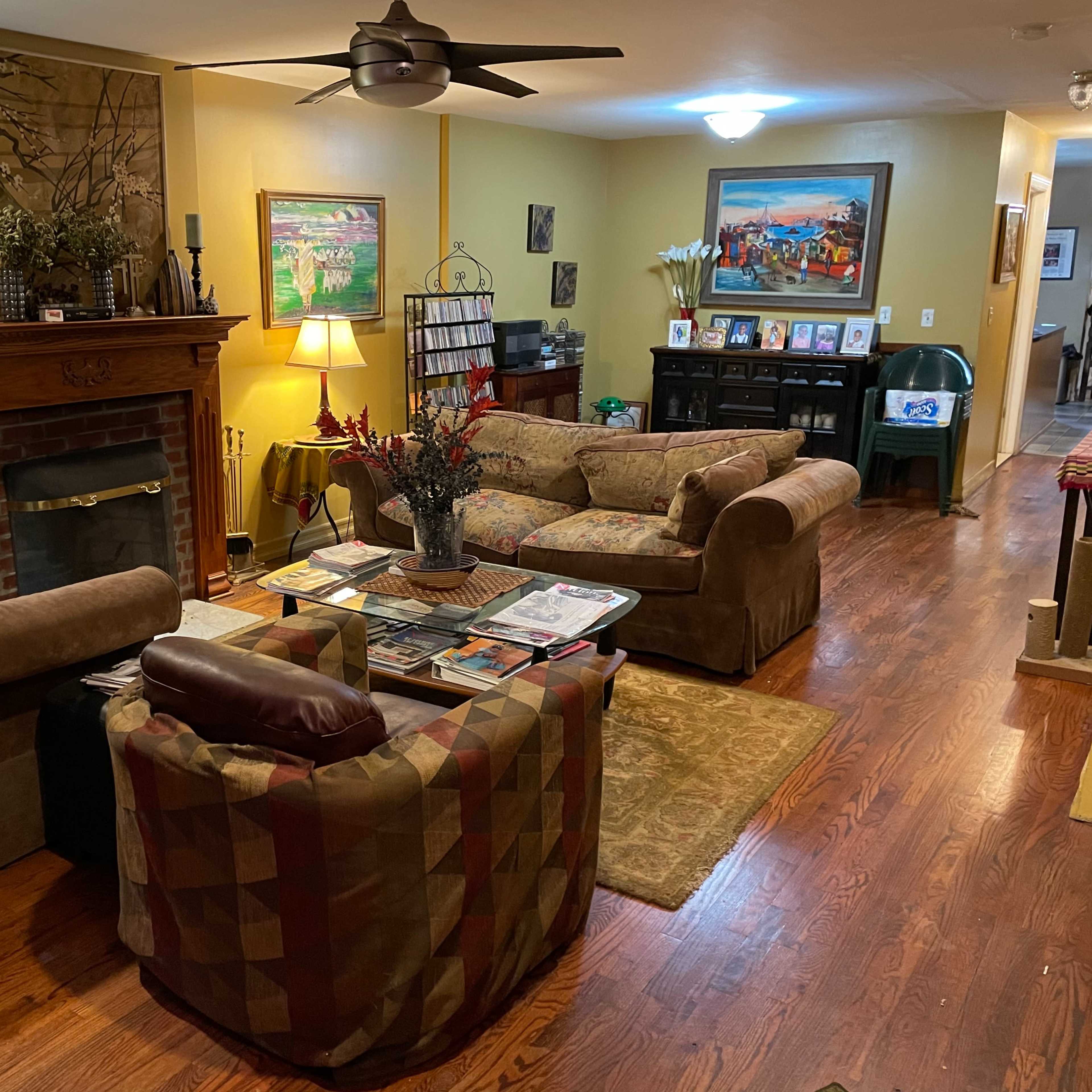 The living room features two couches facing a coffee table, with a fireplace and decorative artwork on the walls.