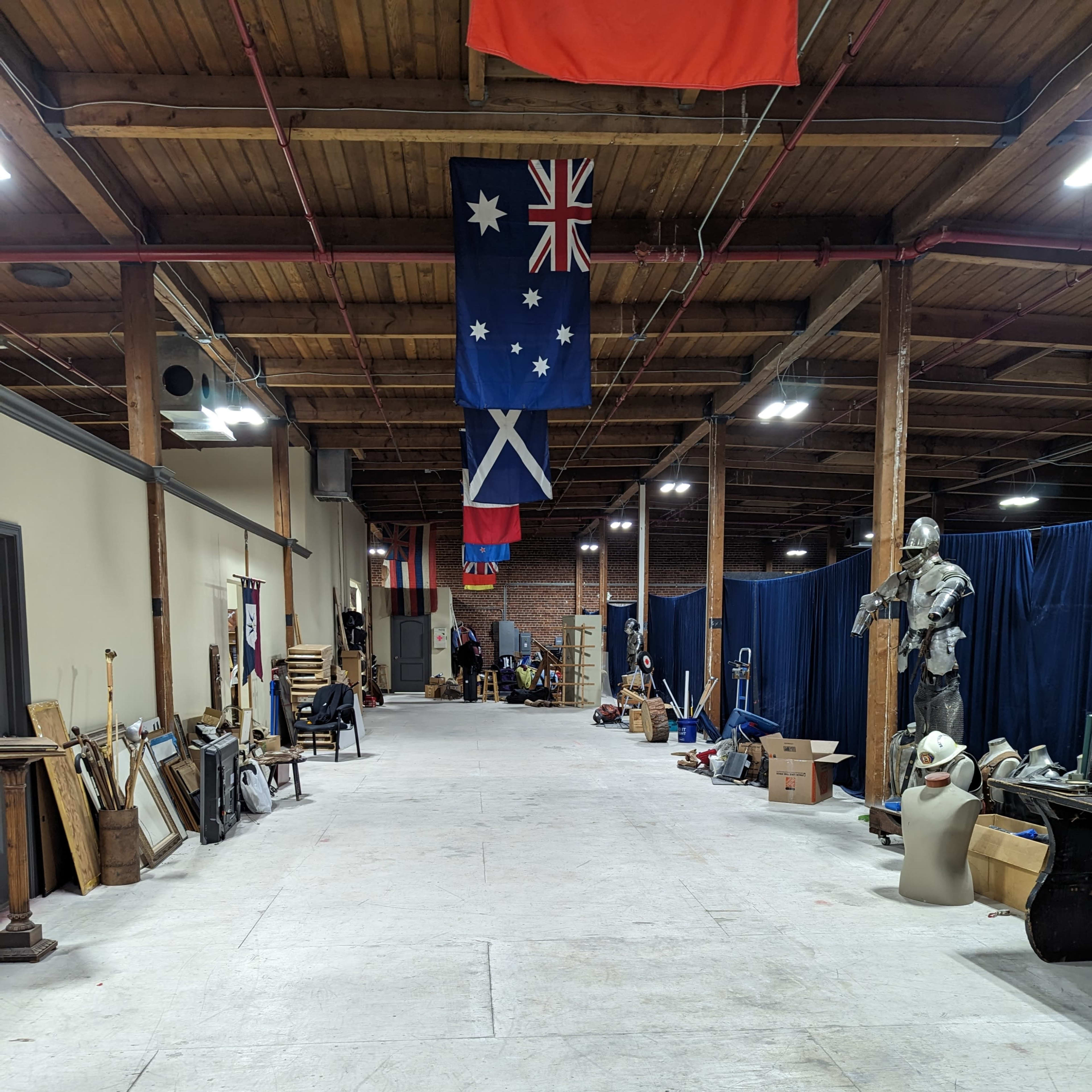 A long, empty hallway in a warehouse with various items and flags hanging from the ceiling.