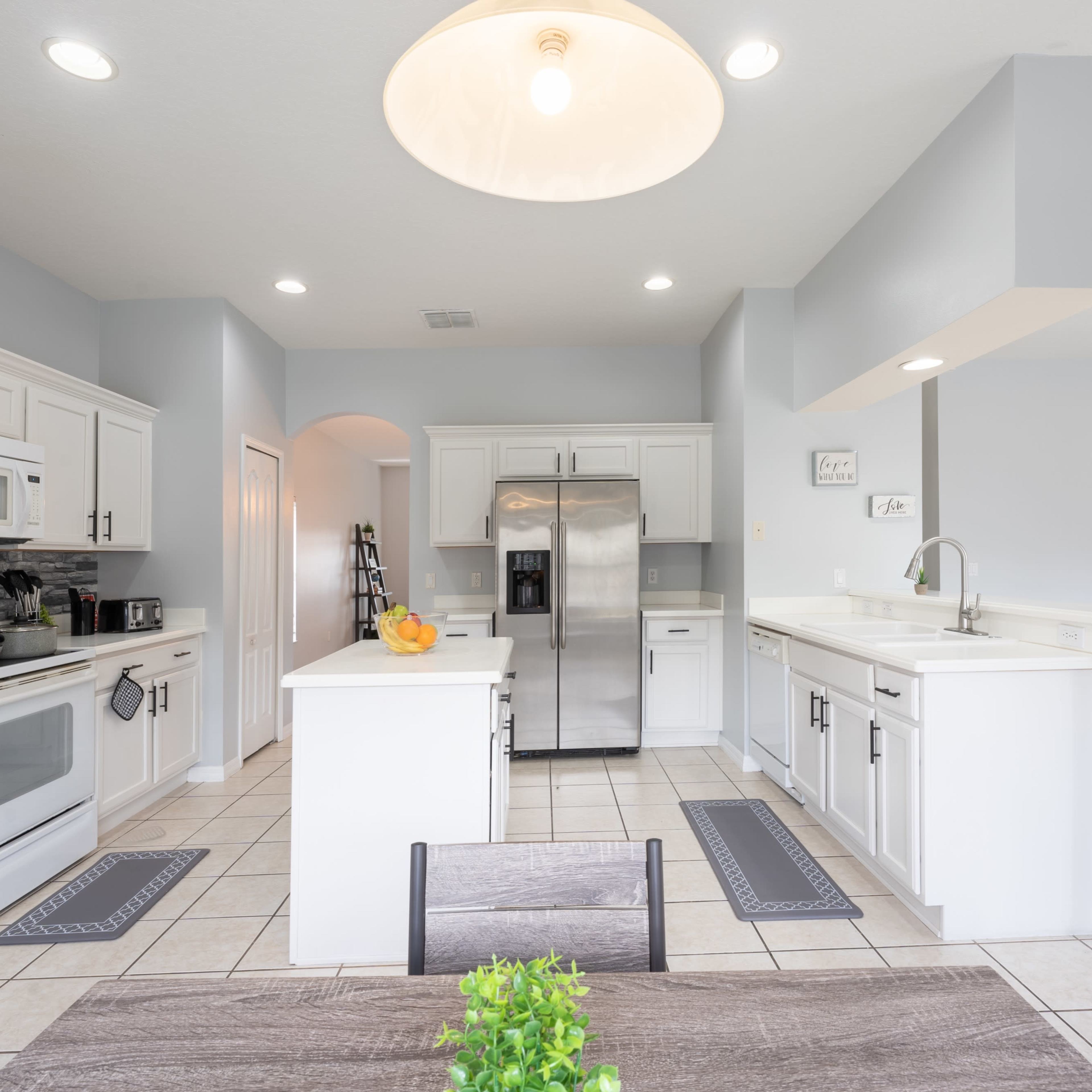 A modern kitchen features white cabinetry, stainless steel appliances, and a central island with bar seating.