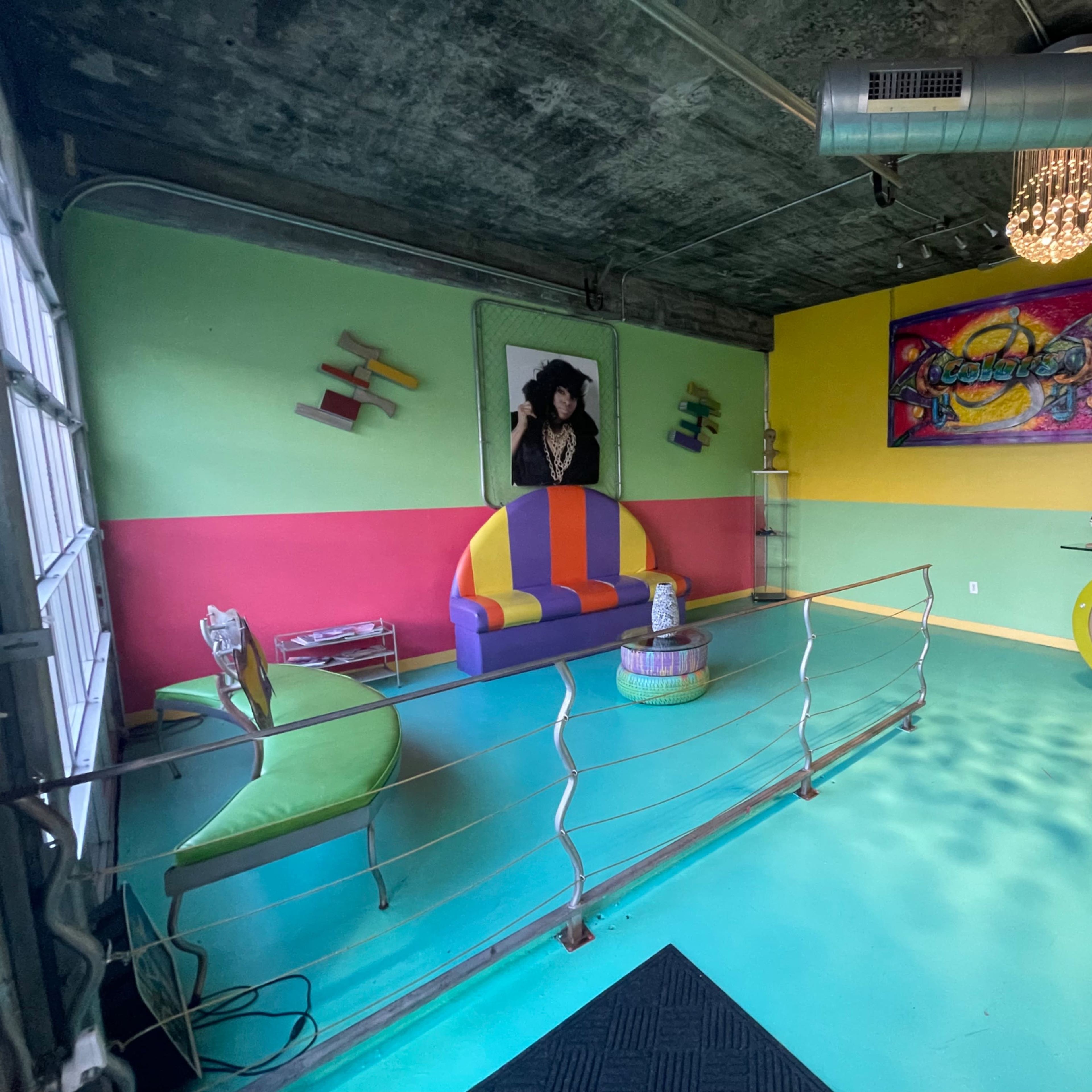 A colorful lounge space featuring a multi-colored seating area, vibrant wall art, and a polished turquoise floor.