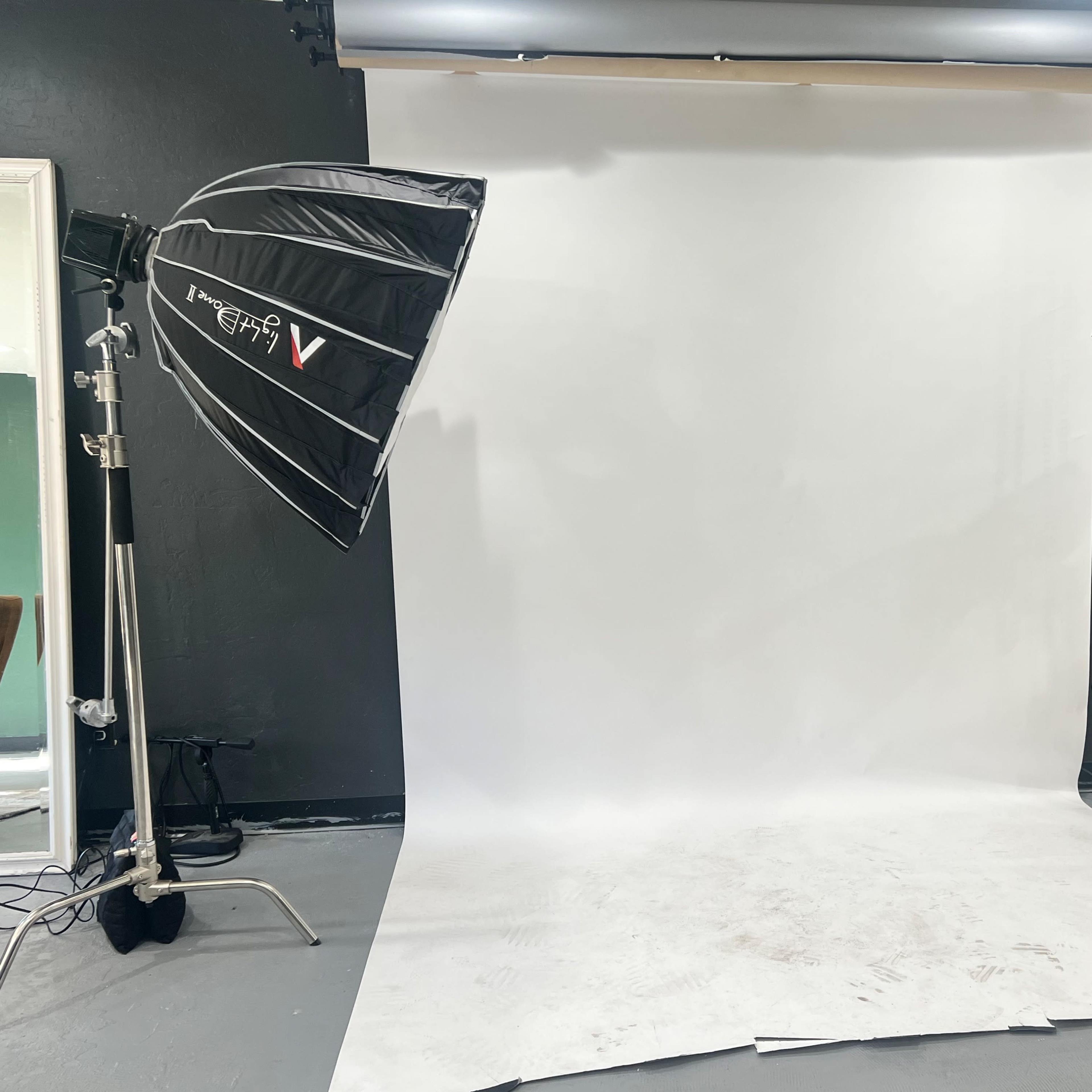 A photography studio setup with a large white backdrop and two light sources positioned on either side.