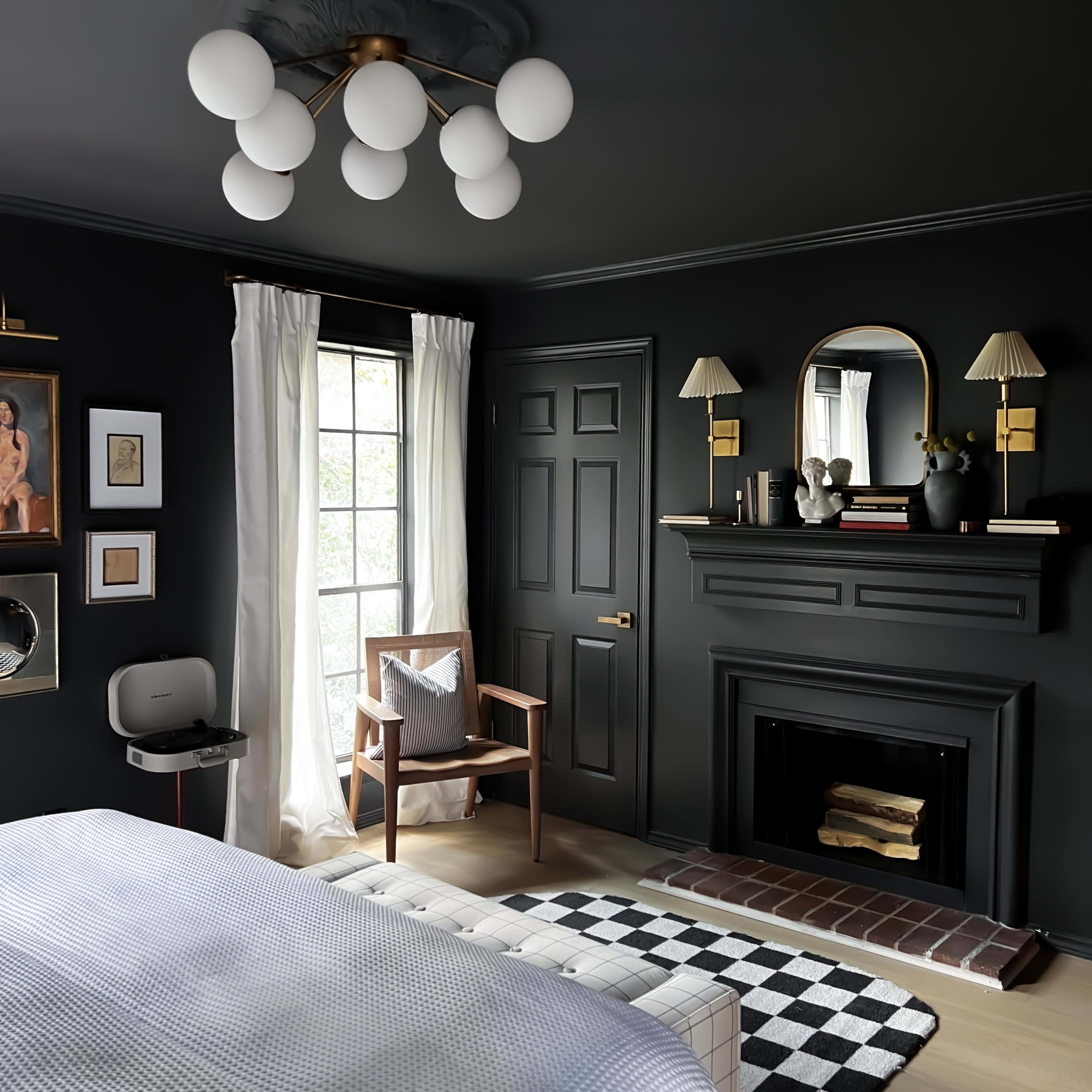 A modern bedroom with dark walls, a fireplace, large round light fixtures, and a combination of decorative elements including framed artwork and a checkered rug.