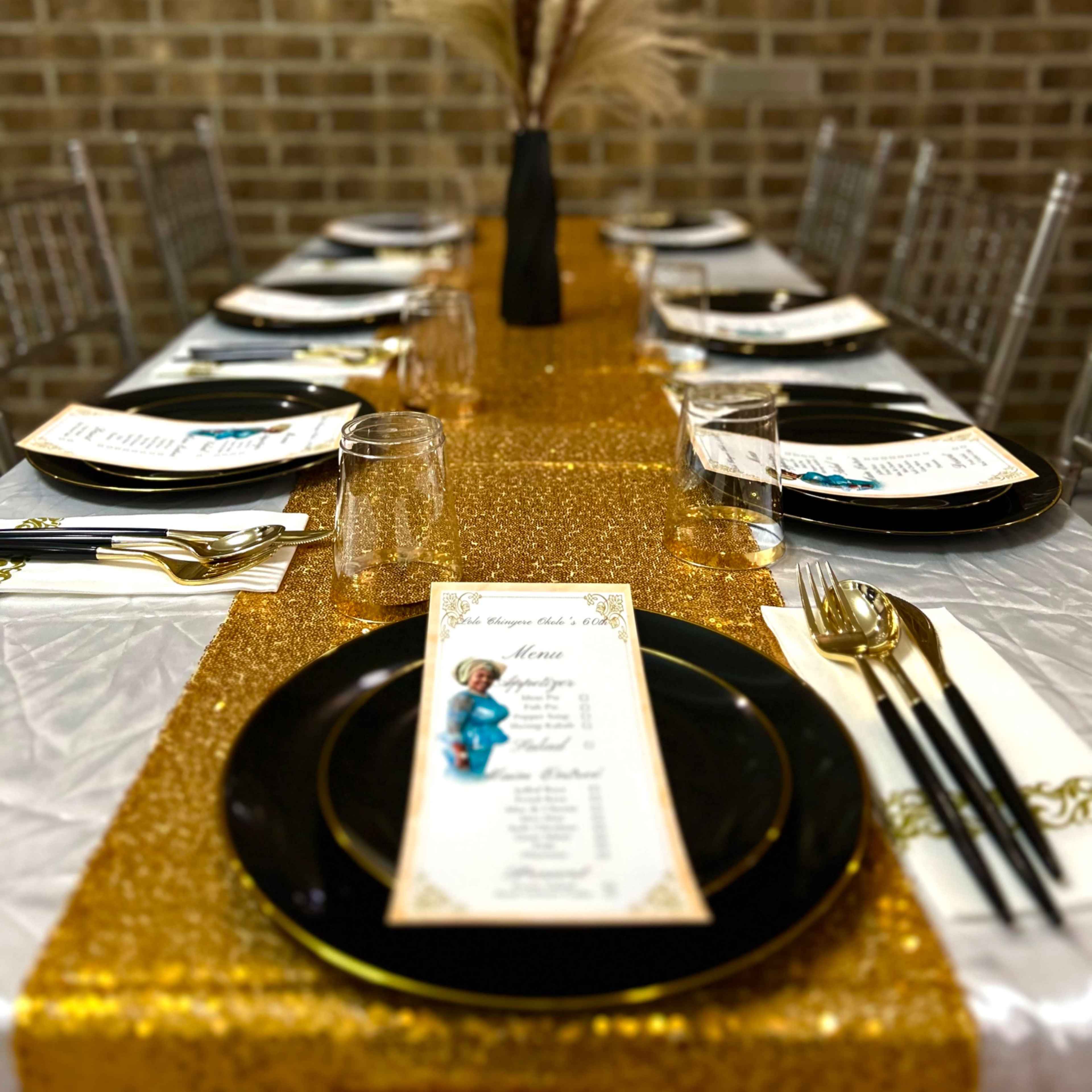 A neatly set dining table features gold and black tableware with a decorative vase and menu cards.