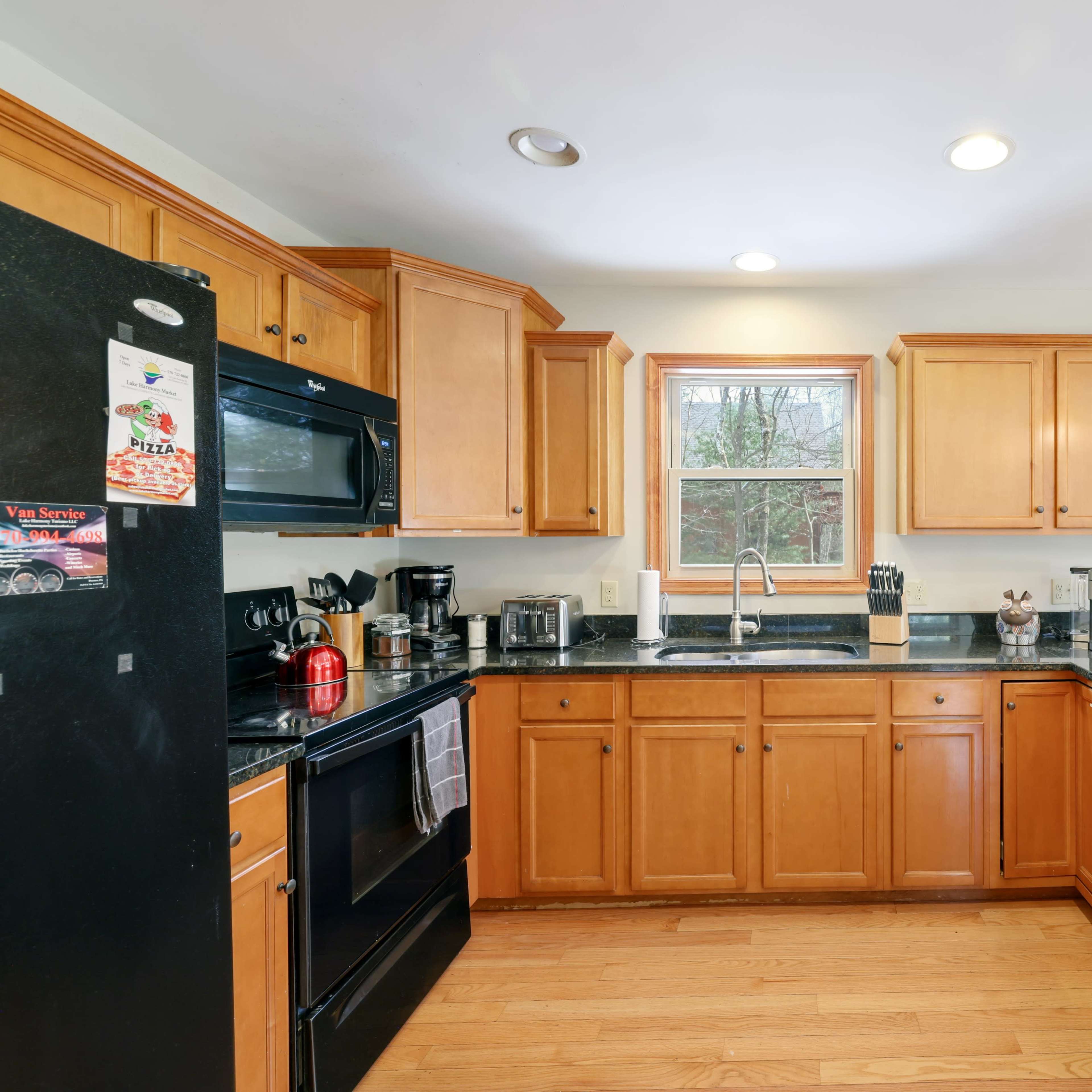 The kitchen features wooden cabinetry, black appliances, and a countertop with a window view.