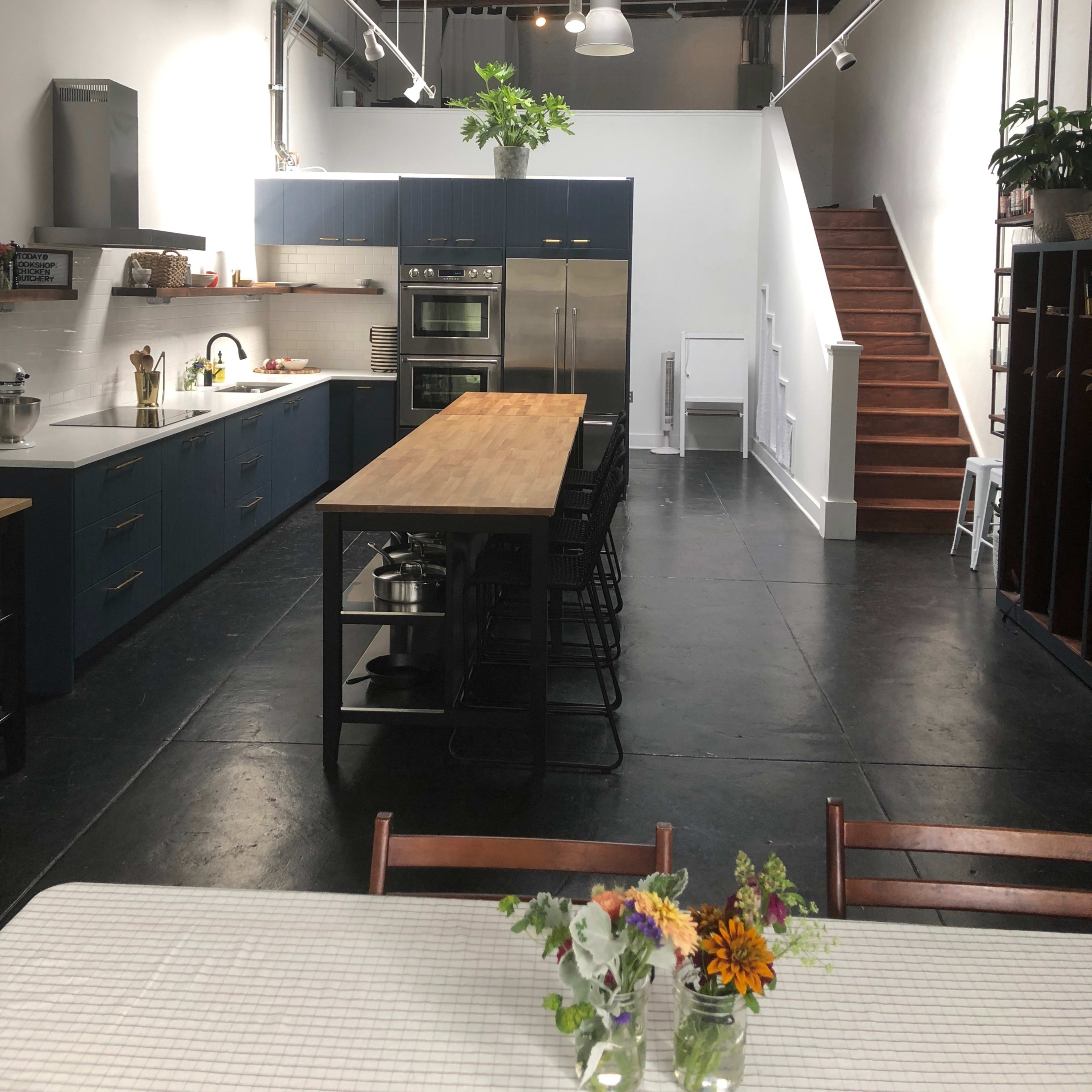 A spacious modern kitchen with a large wooden island, stainless steel appliances, and a staircase leading to an upper level.
