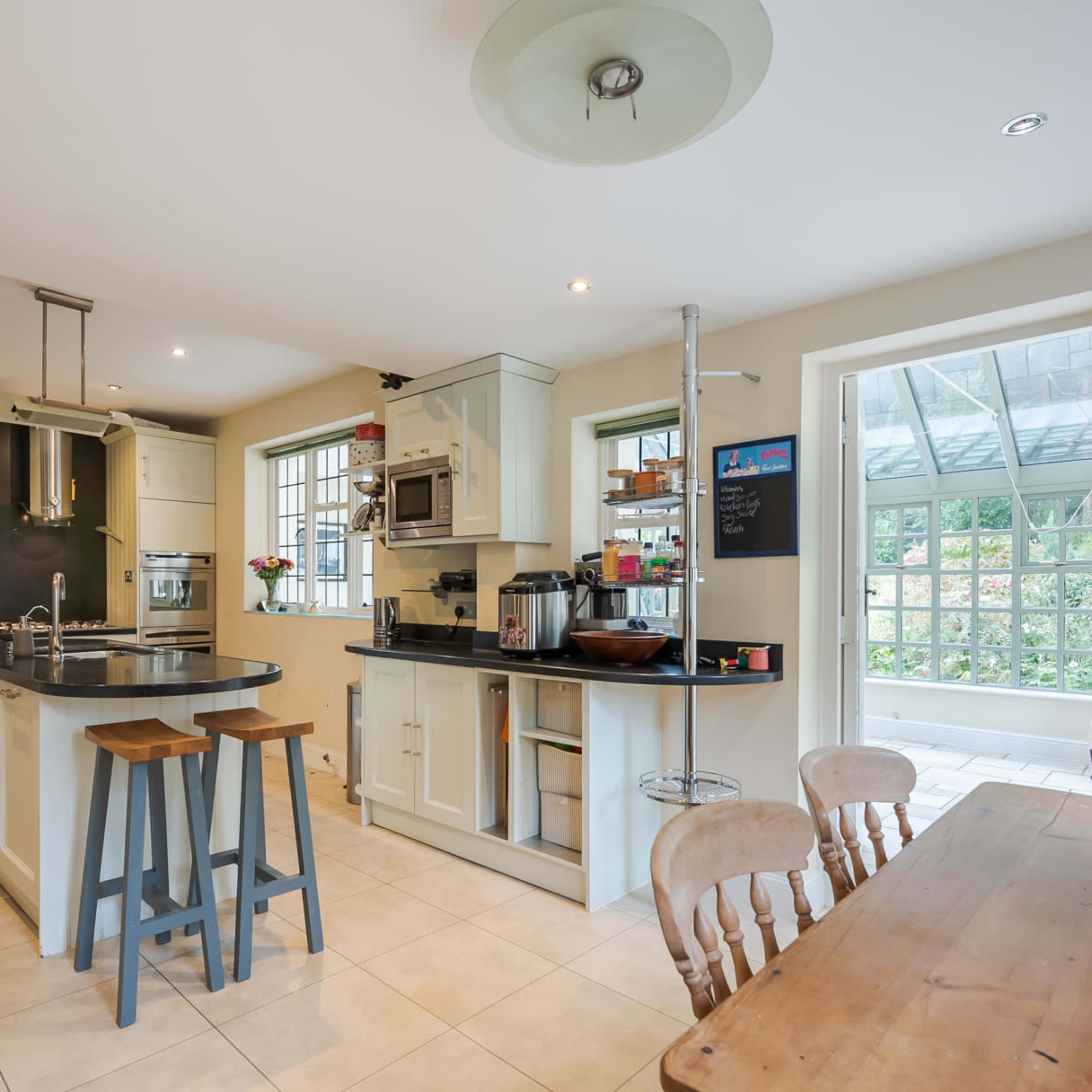 A modern kitchen with a central island, stainless steel appliances, and a dining area featuring a wooden table and chairs.