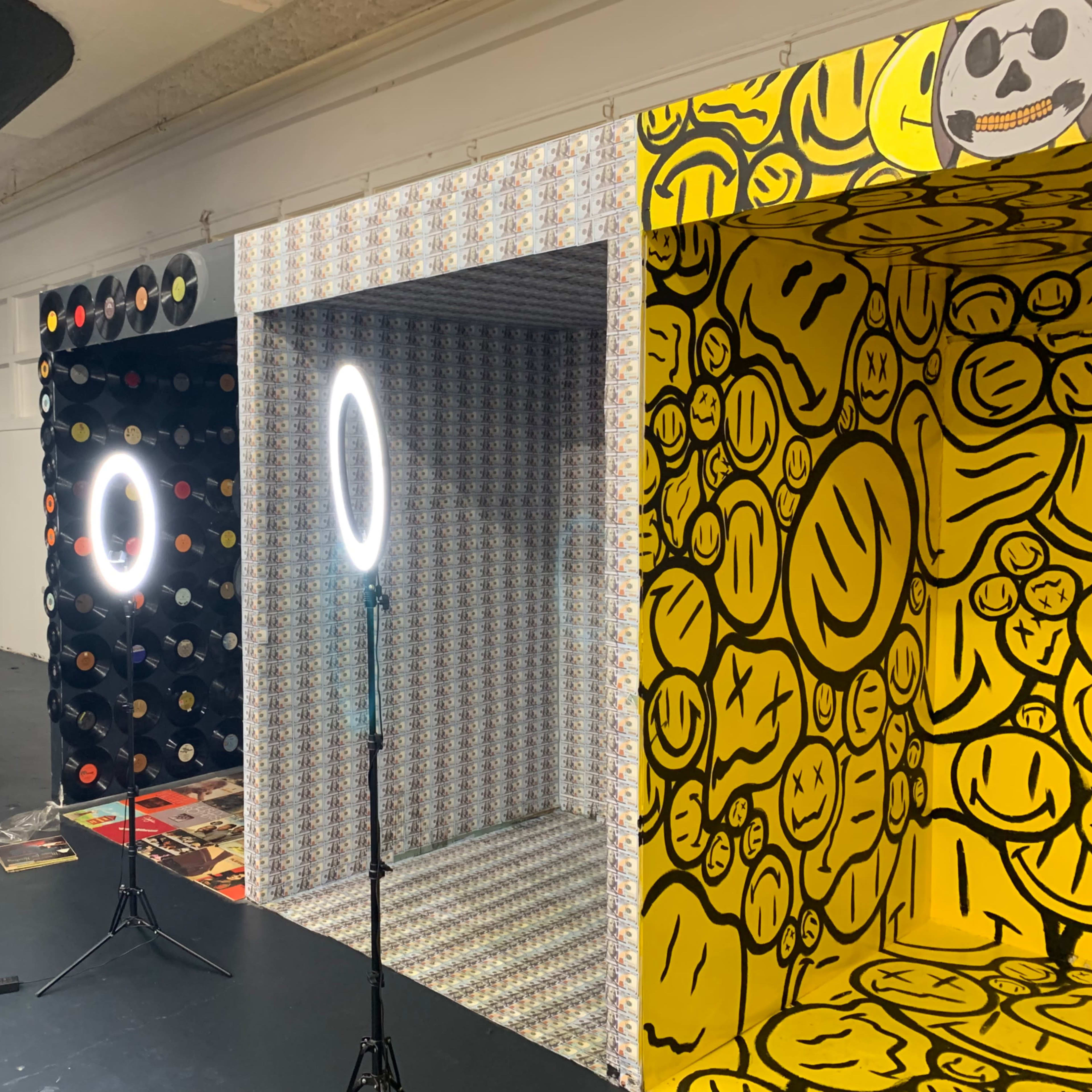 A room with three alcoves featuring patterned backgrounds, two ring lights on stands, and a stool nearby.