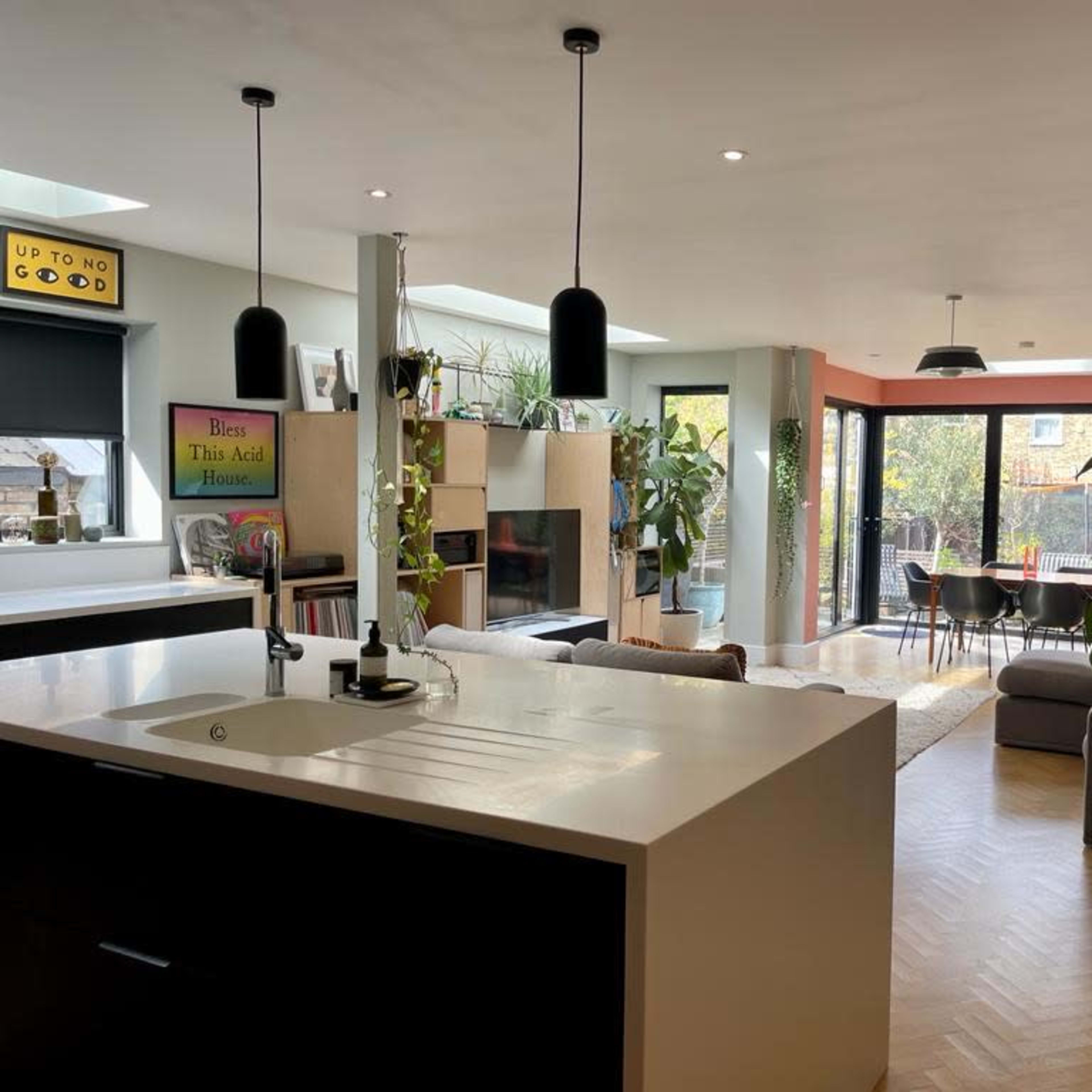 An open-concept living space with a modern kitchen on the left and a furnished lounge area with large windows on the right.