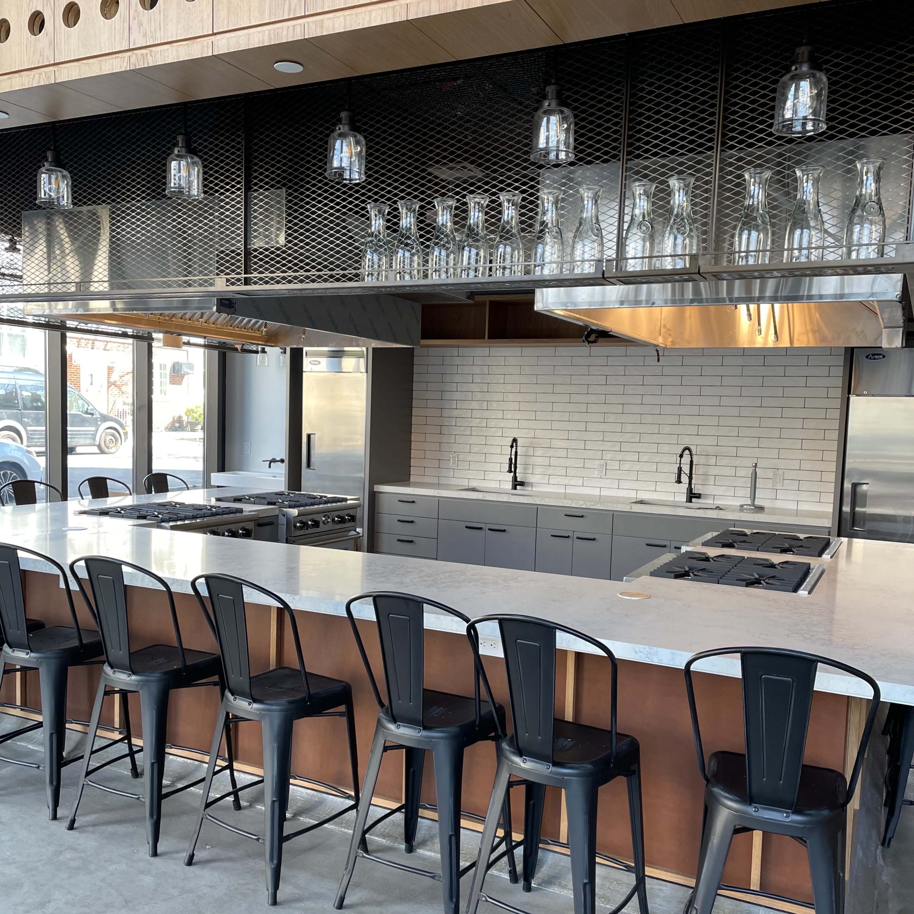 A modern kitchen with a large island, bar stools, and stainless steel appliances, featuring a sleek design and open layout.
