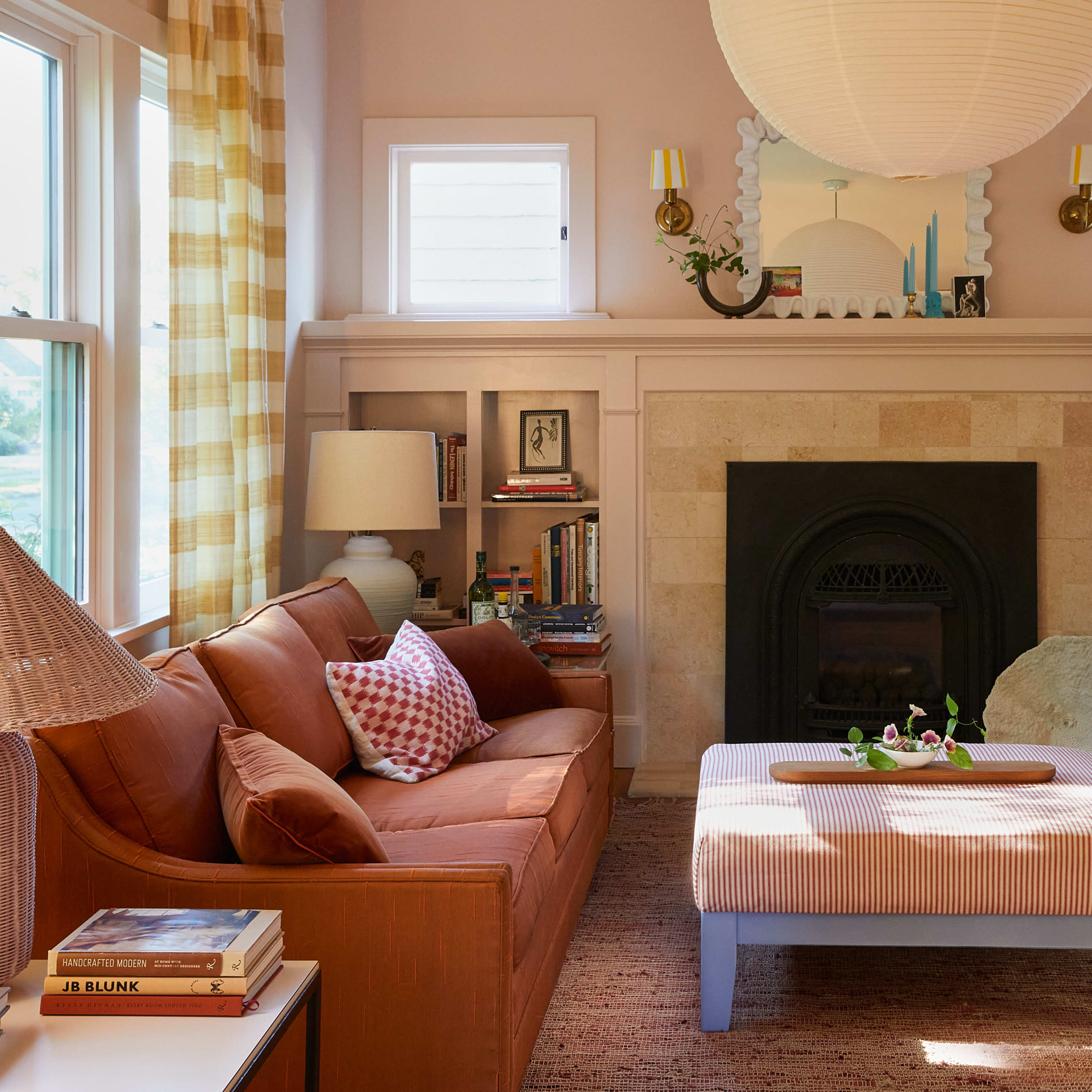 A living room with two couches, a central coffee table, and bookshelves, featuring natural light from windows and a decorative fireplace.