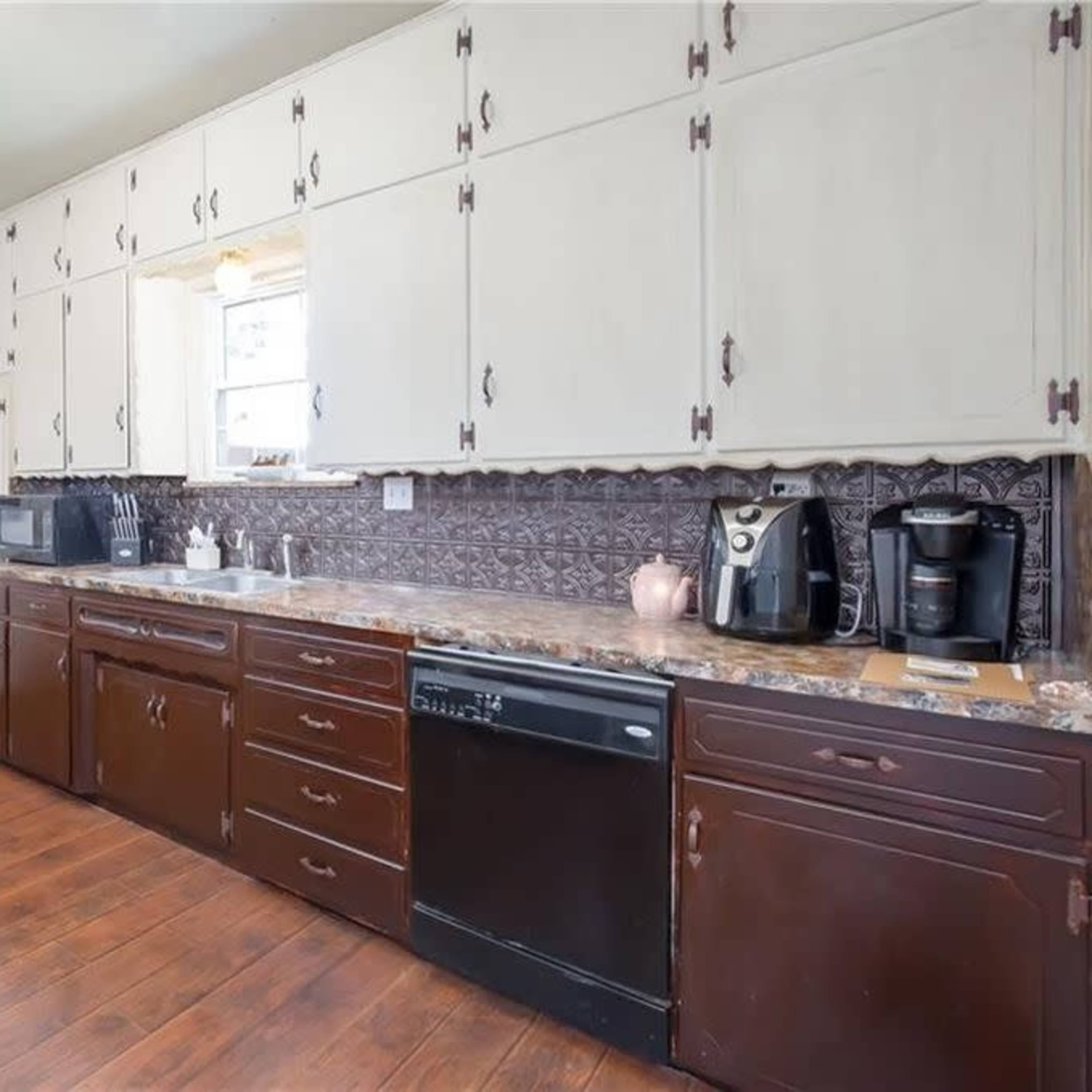 A kitchen with dark wooden cabinets, a granite countertop, and various appliances including a coffee maker and a microwave.