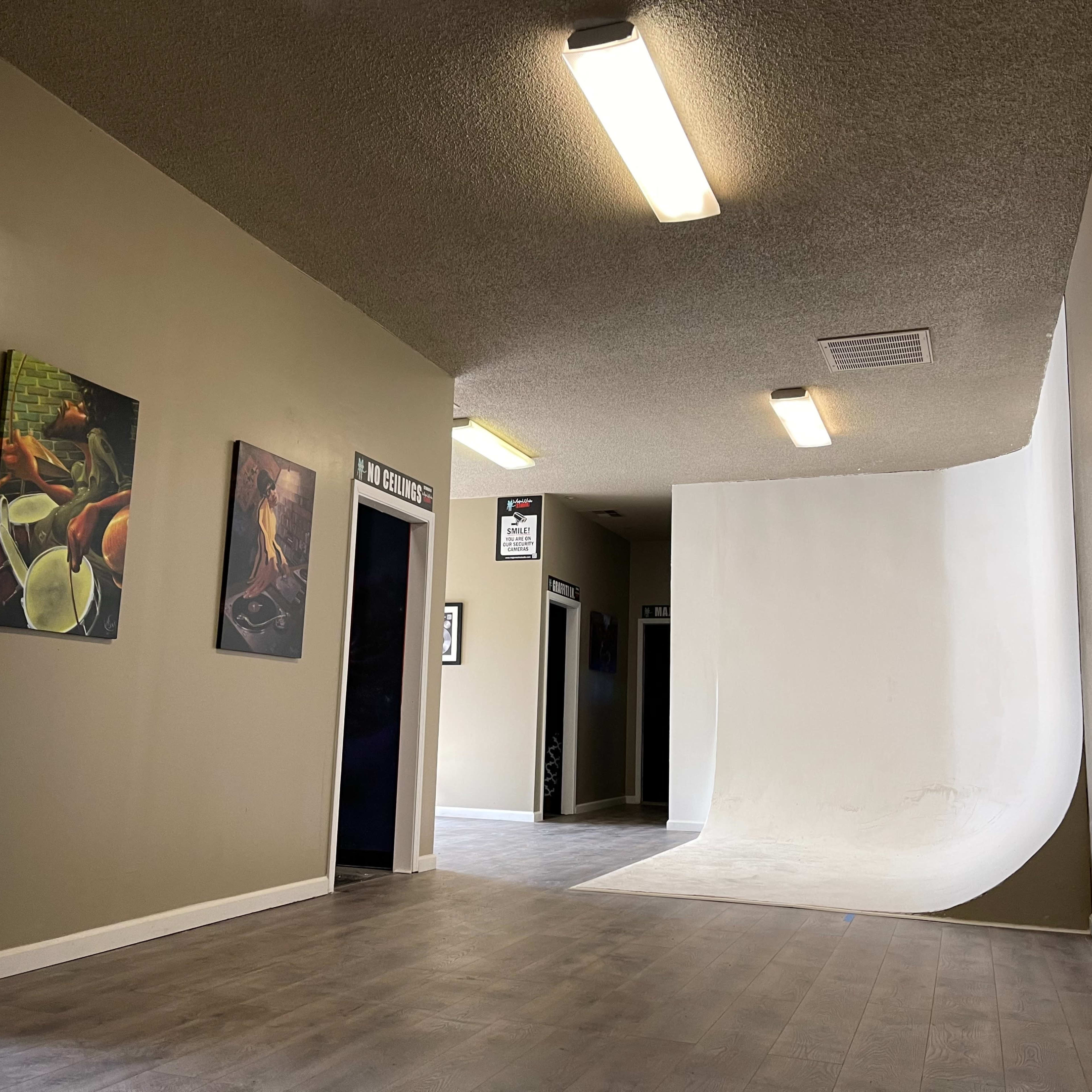 A hallway with light-colored walls and a smooth, curved backdrop at the end, accompanied by framed artwork on one side.