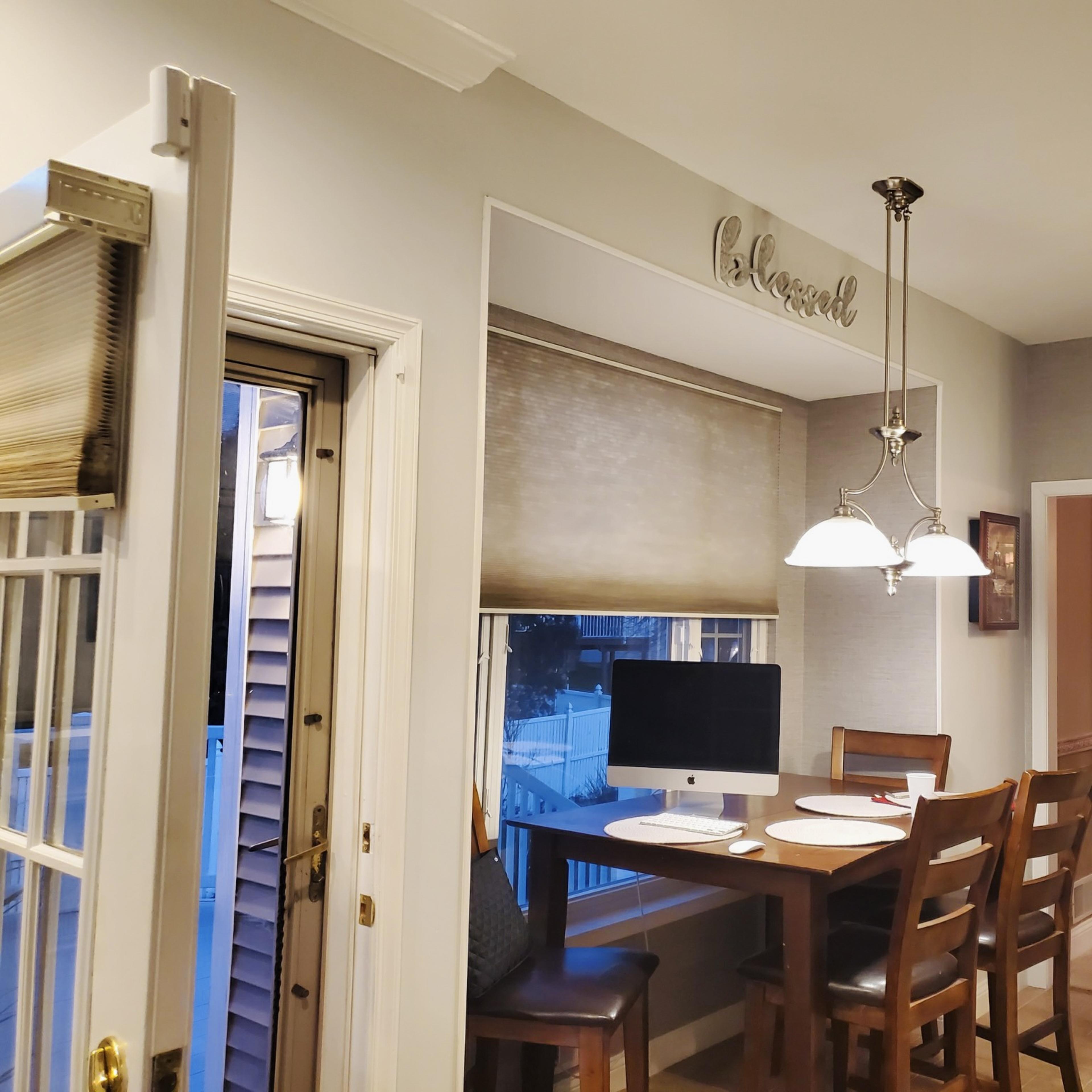 A kitchen featuring a small dining area with a table, chairs, and a computer near a window.