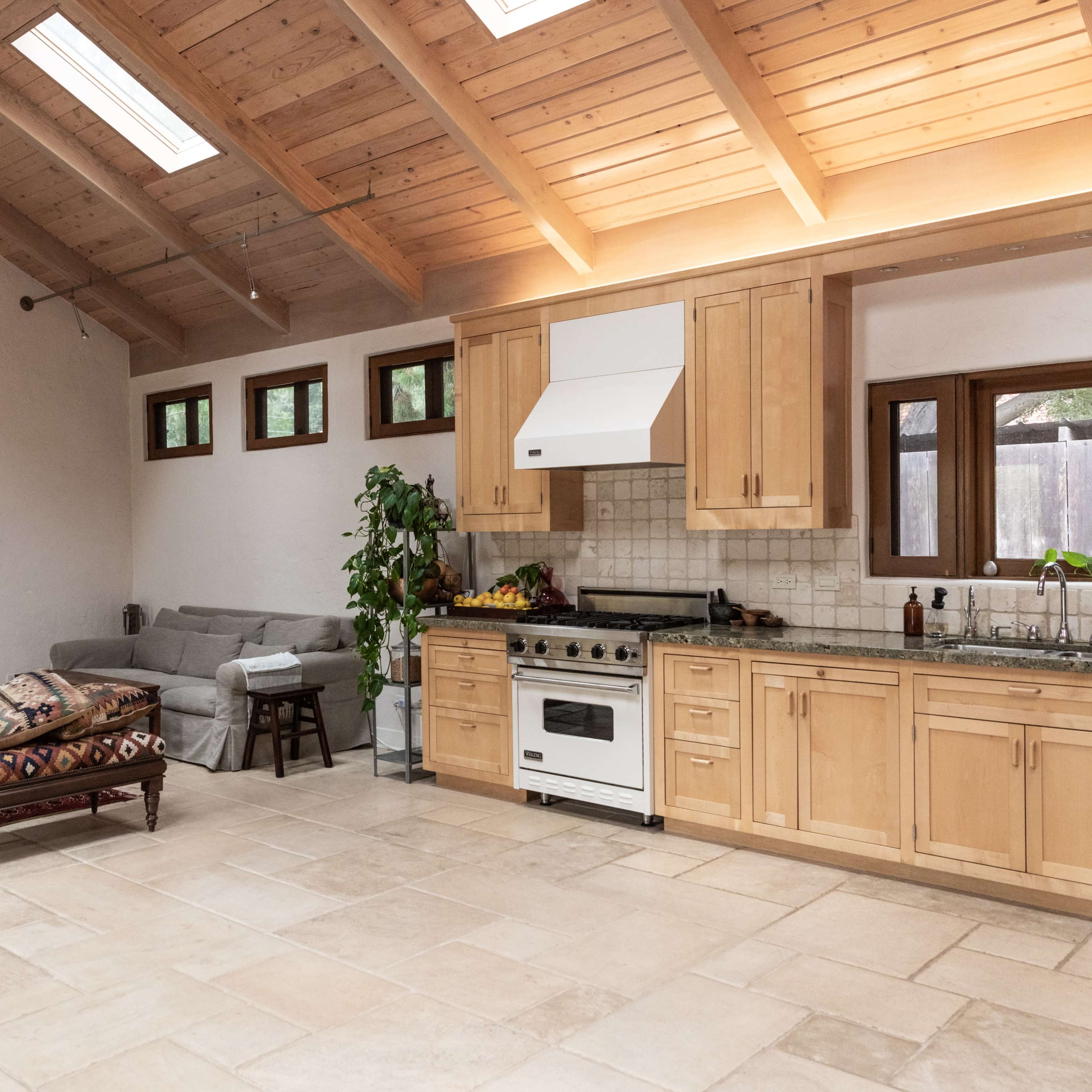 An open kitchen and living area with wooden beams, a fireplace, and a mix of furniture and decor.