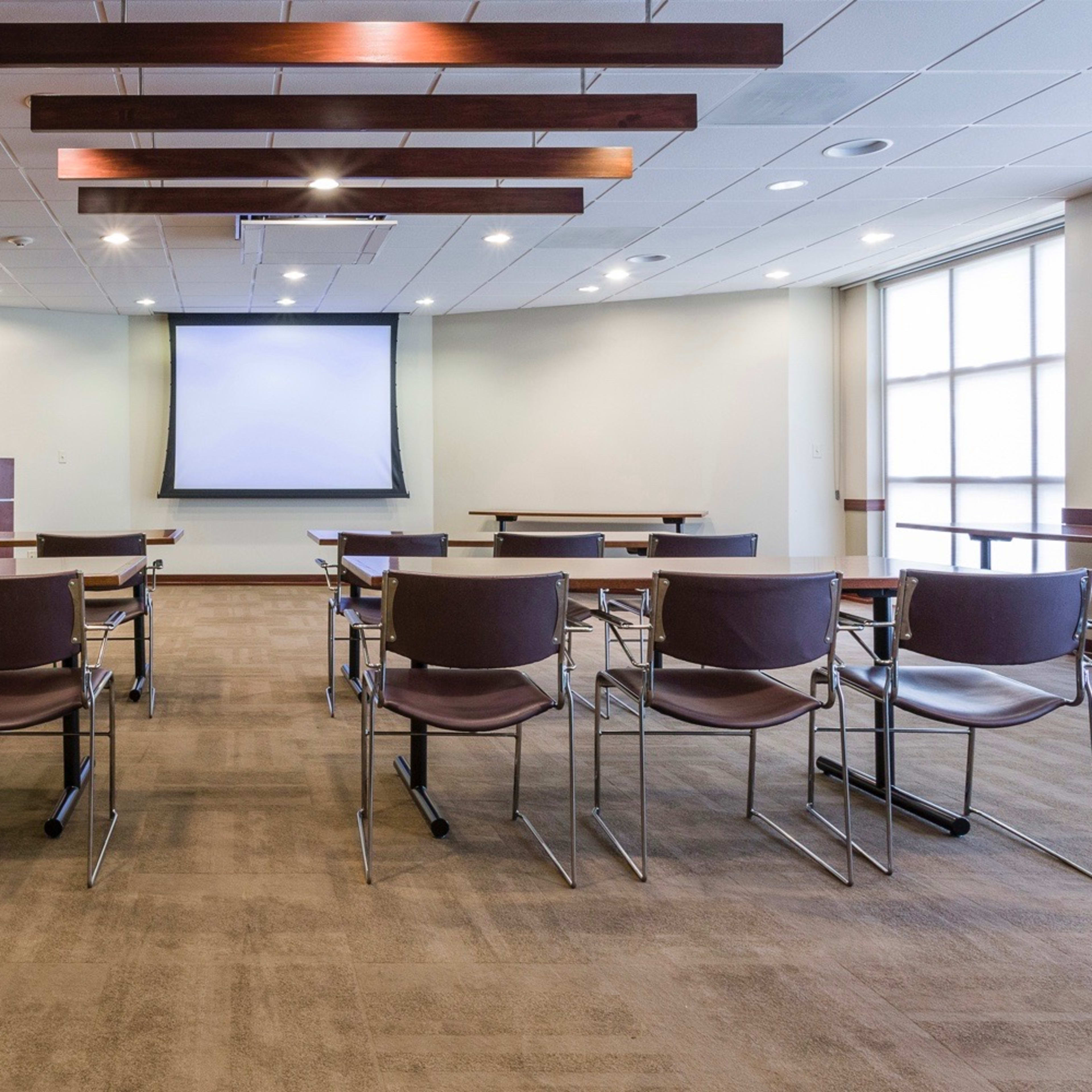 A seminar room arranged with several rows of chairs facing a projector screen at the front.