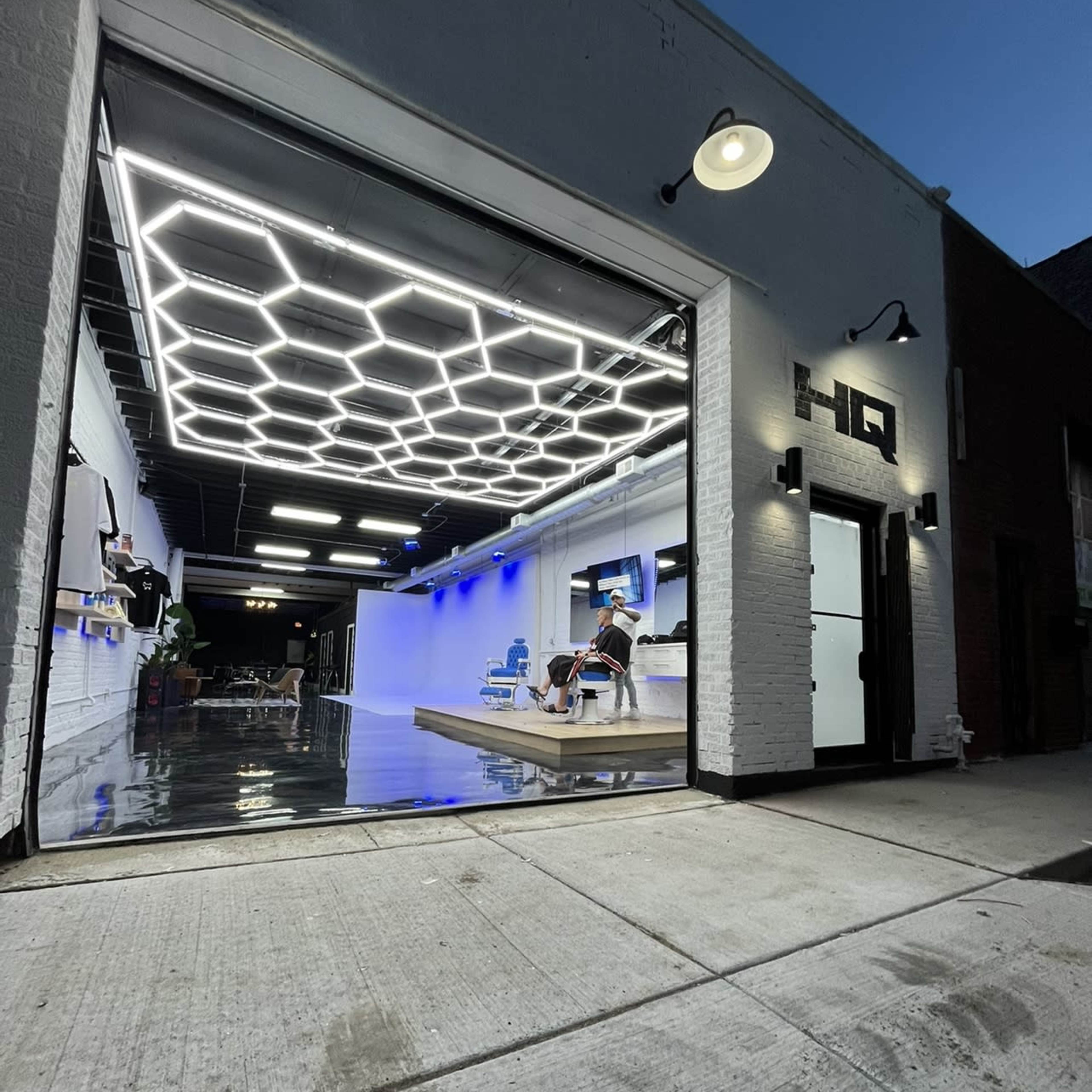 A modern garage space with a hexagonal ceiling light design, partially open door, and a person seated inside.