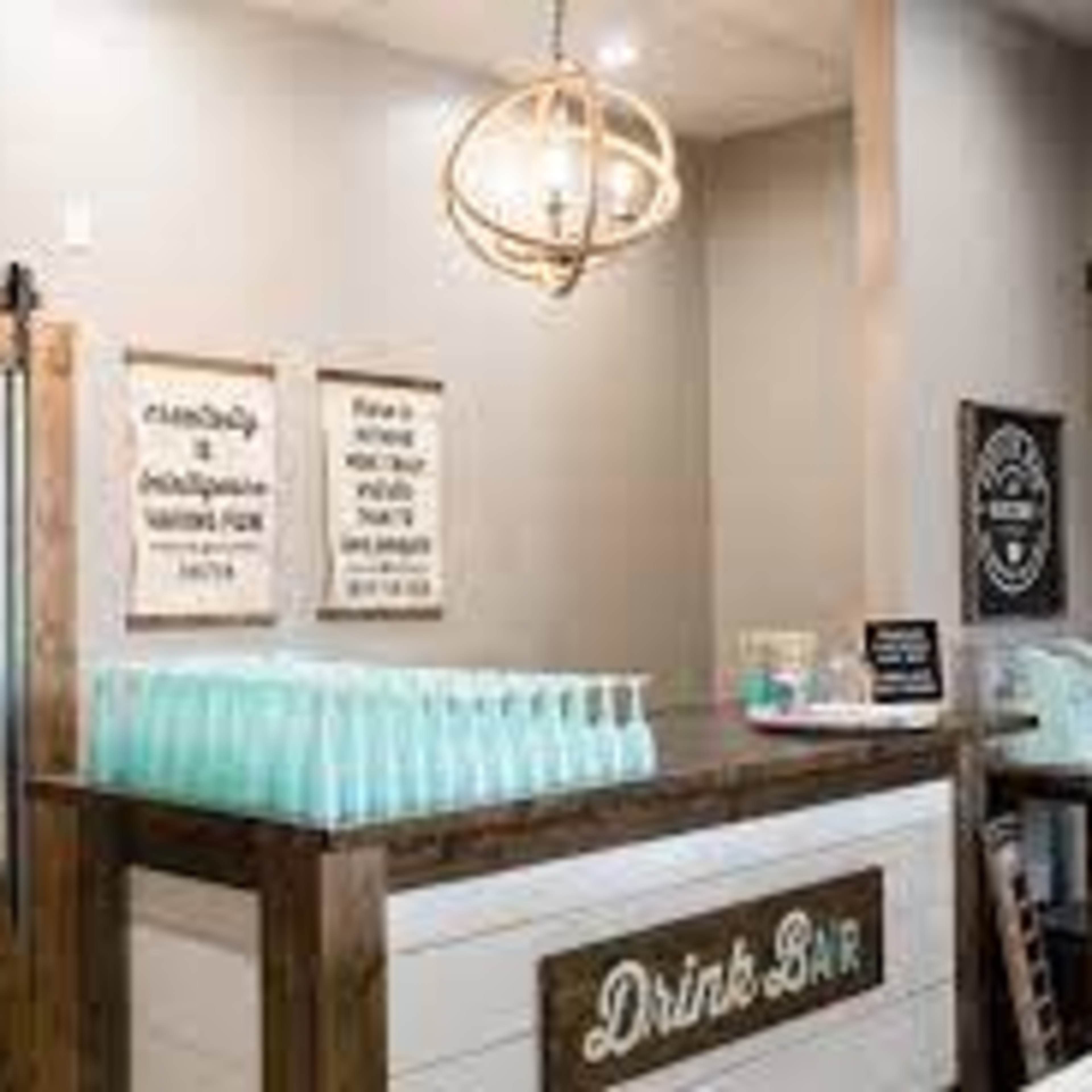 A drink bar featuring a wooden counter with glass bottles and a variety of signs on the walls.