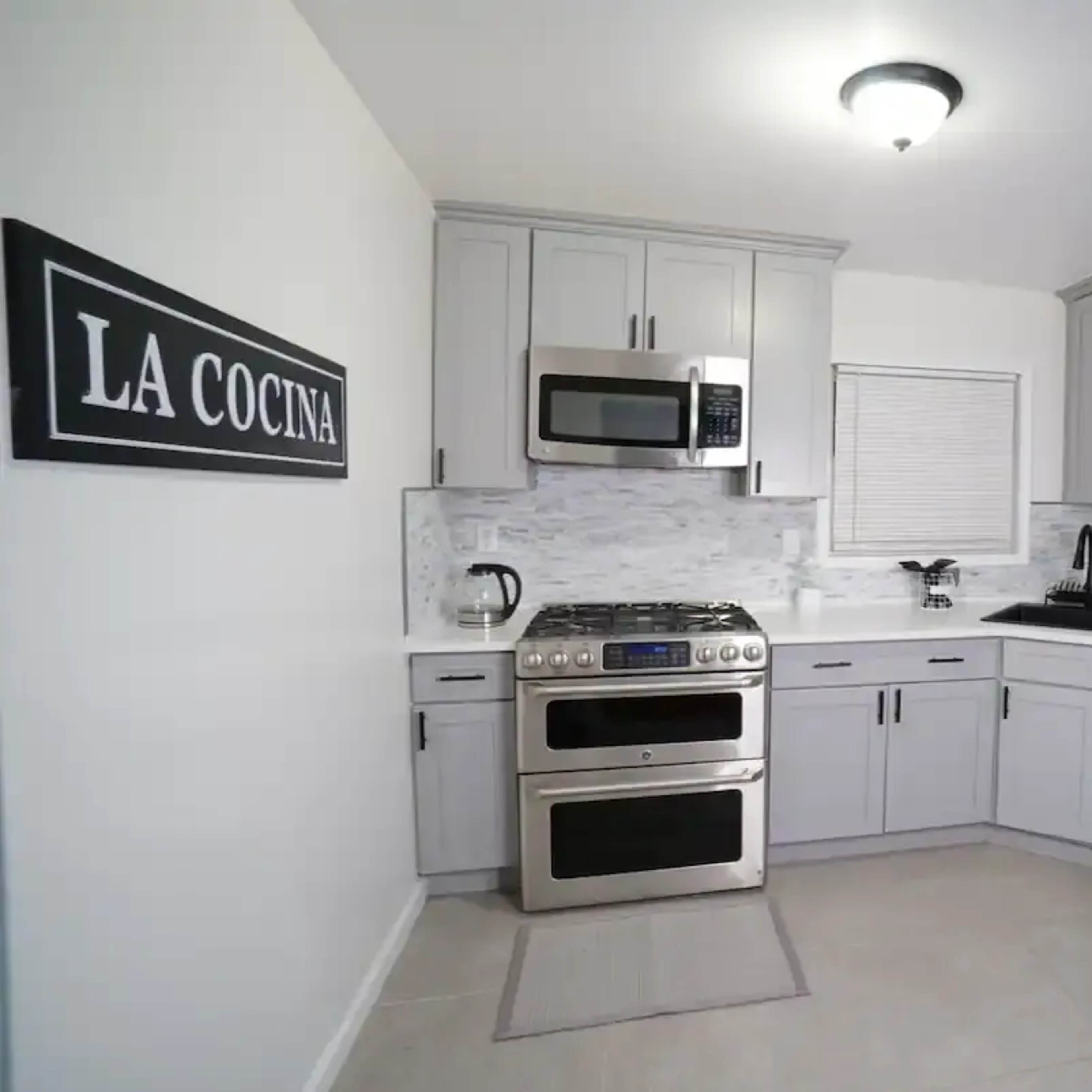 A modern kitchen featuring gray cabinetry, stainless steel appliances, and a white countertop with a tile backsplash.
