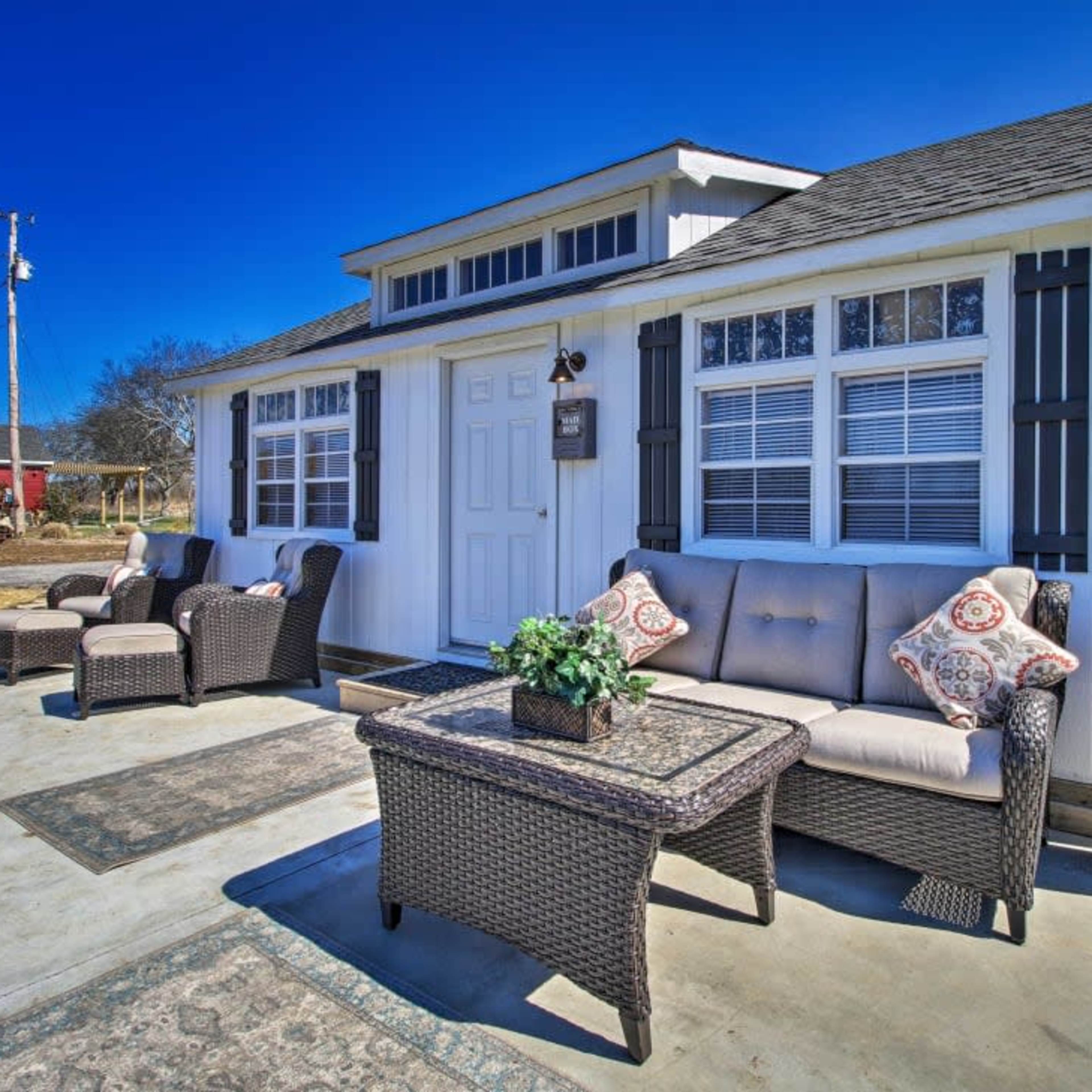 A modern outdoor seating area with wicker furniture and a small table placed in front of a white house.