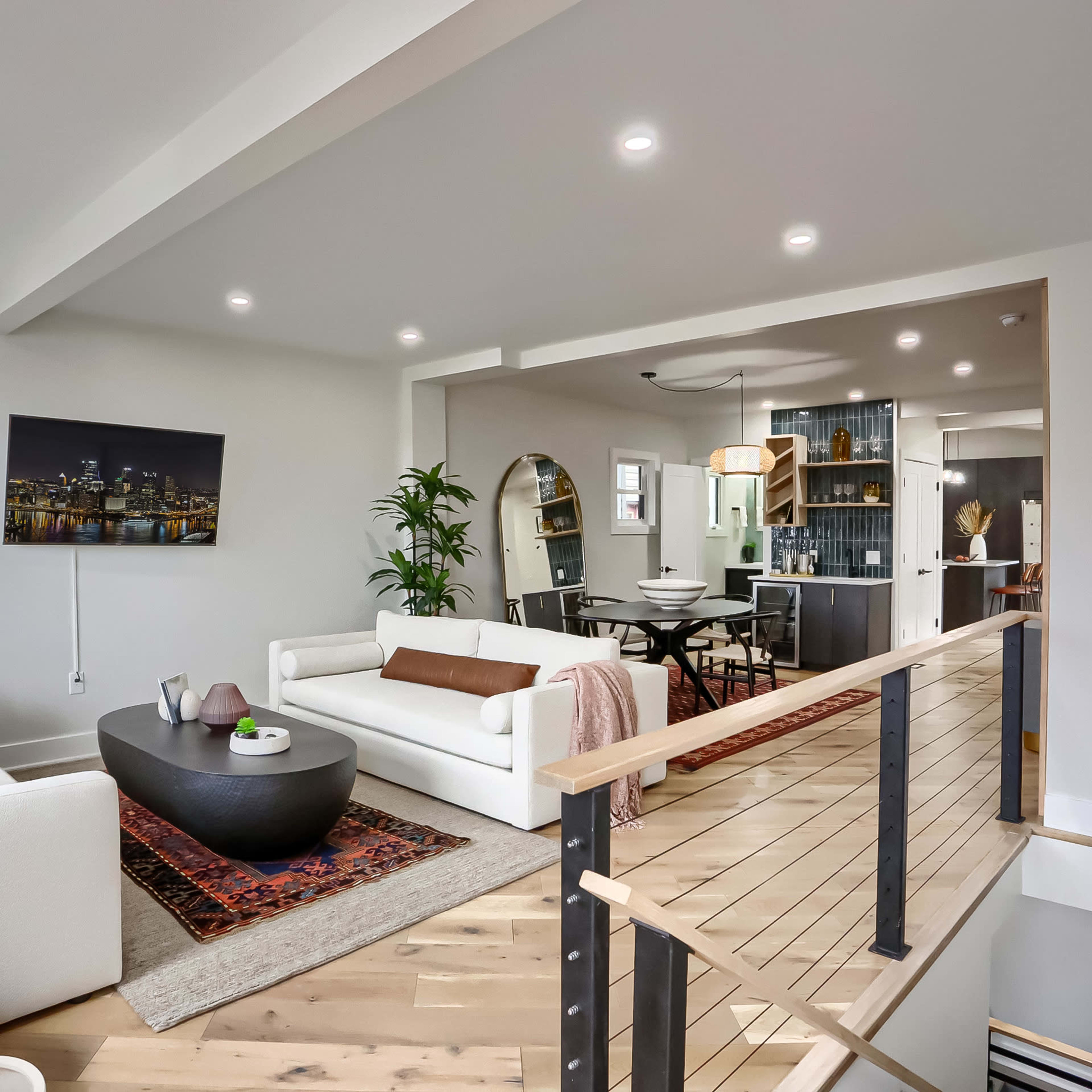 A bright living space features a mix of seating arrangements, a round coffee table in the center, and an open floor plan leading to a dining area.