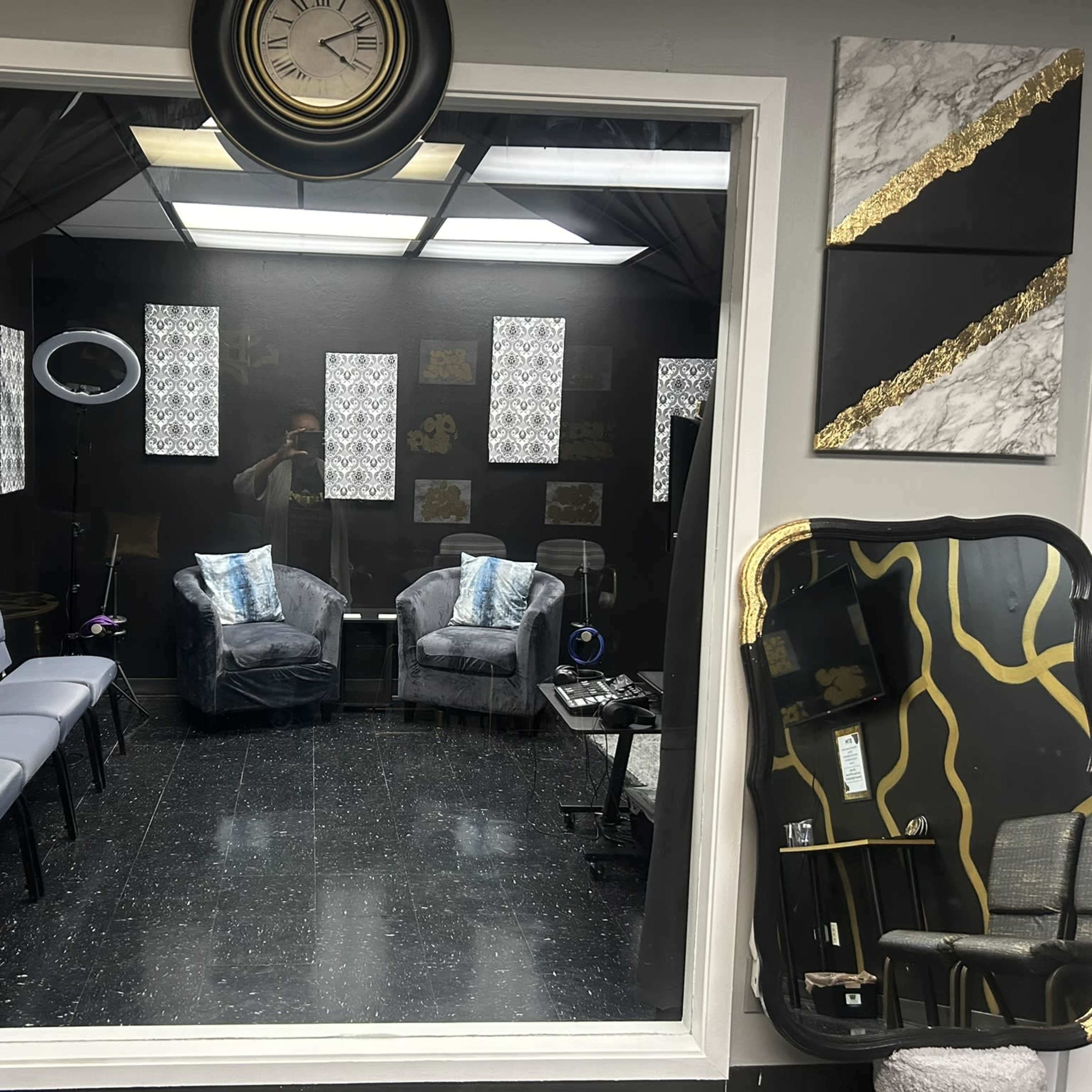 A large mirror frames a waiting area featuring two gray armchairs, a small table, and various decorative elements on the walls.