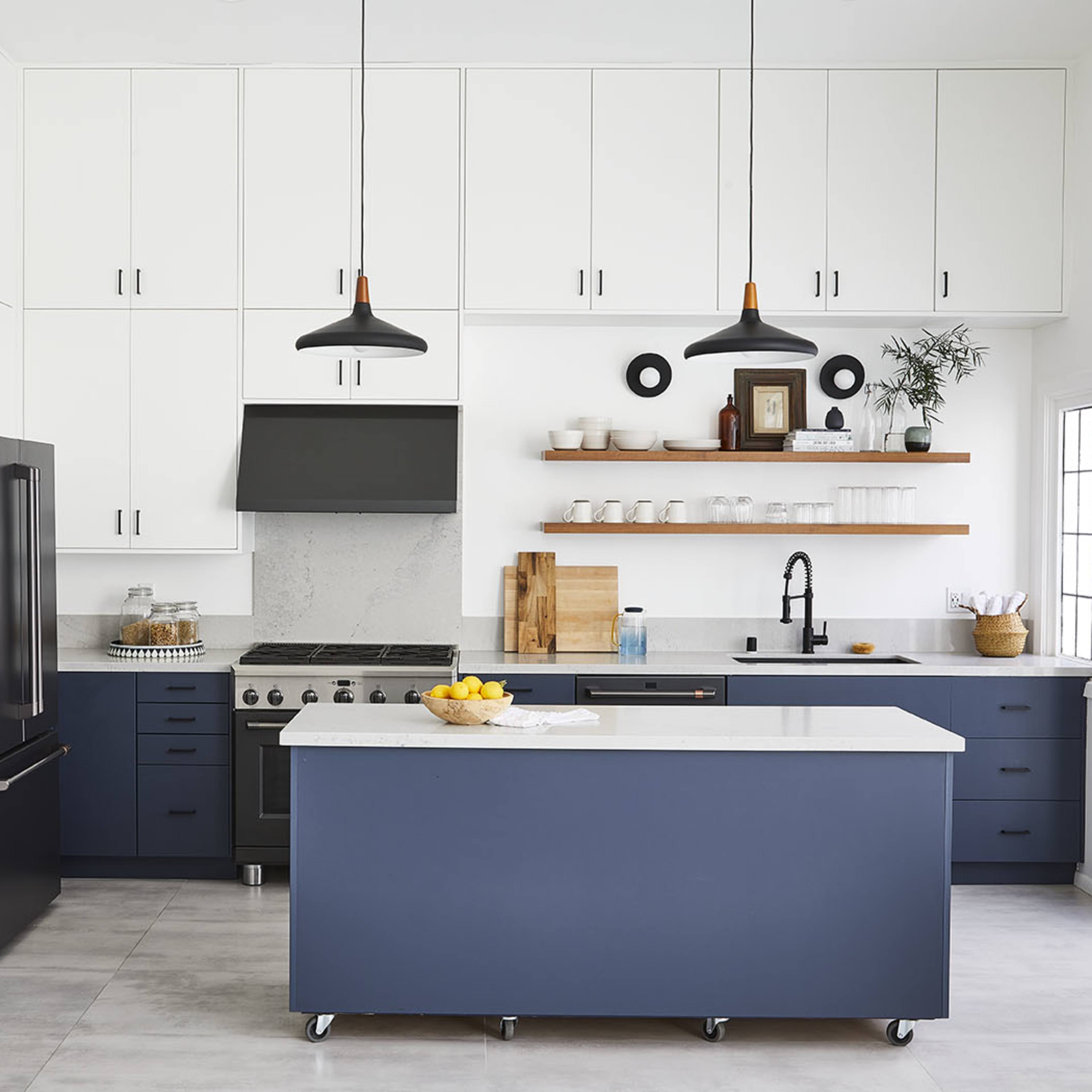 A modern kitchen with navy blue cabinets, a central island, and sleek black appliances against a light-colored backdrop.
