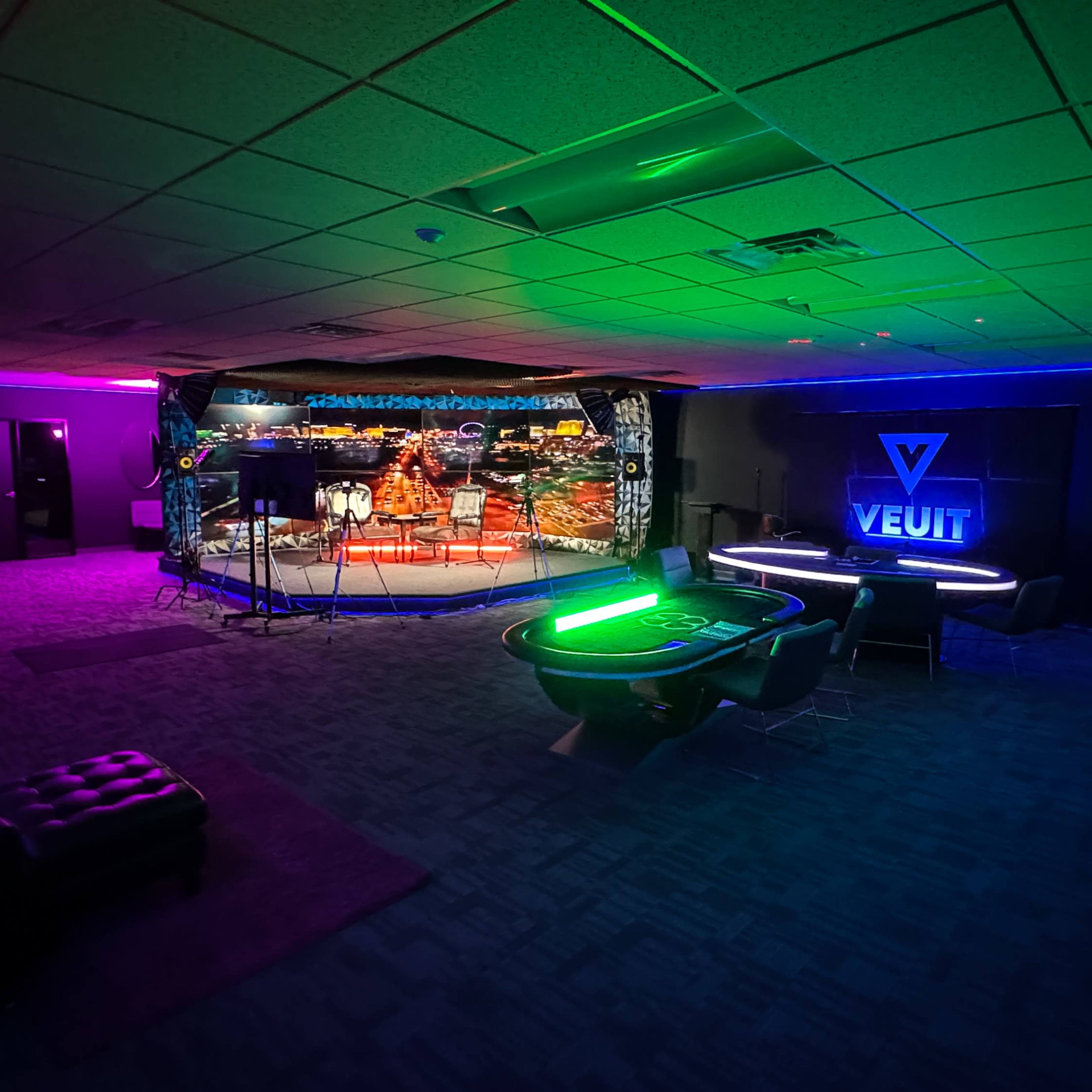 A room designed for entertainment, featuring a green pool table, a sleek bar area, and a backdrop of a cityscape under colorful lighting.