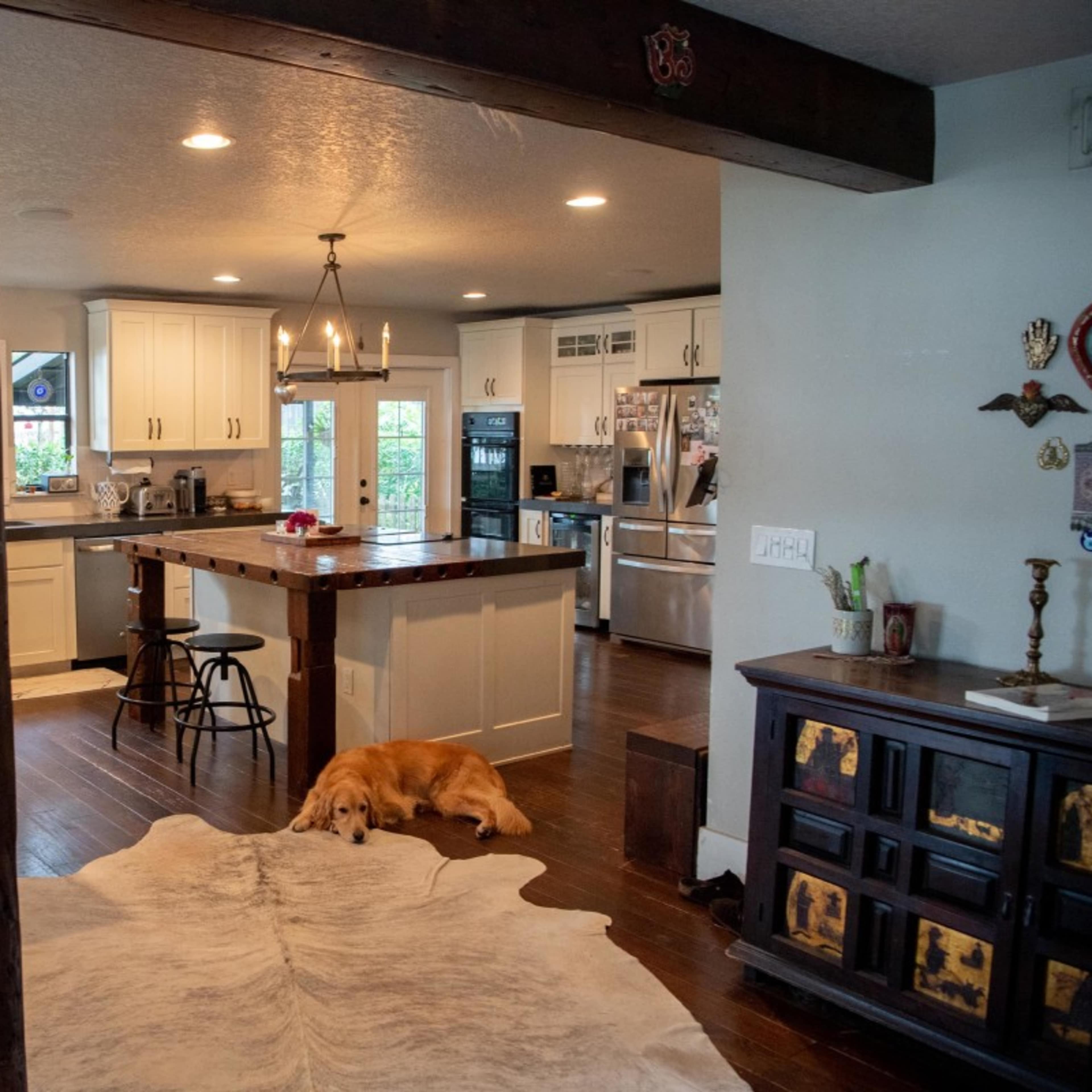 A spacious kitchen features a large island with a golden retriever resting on a rug in the foreground.