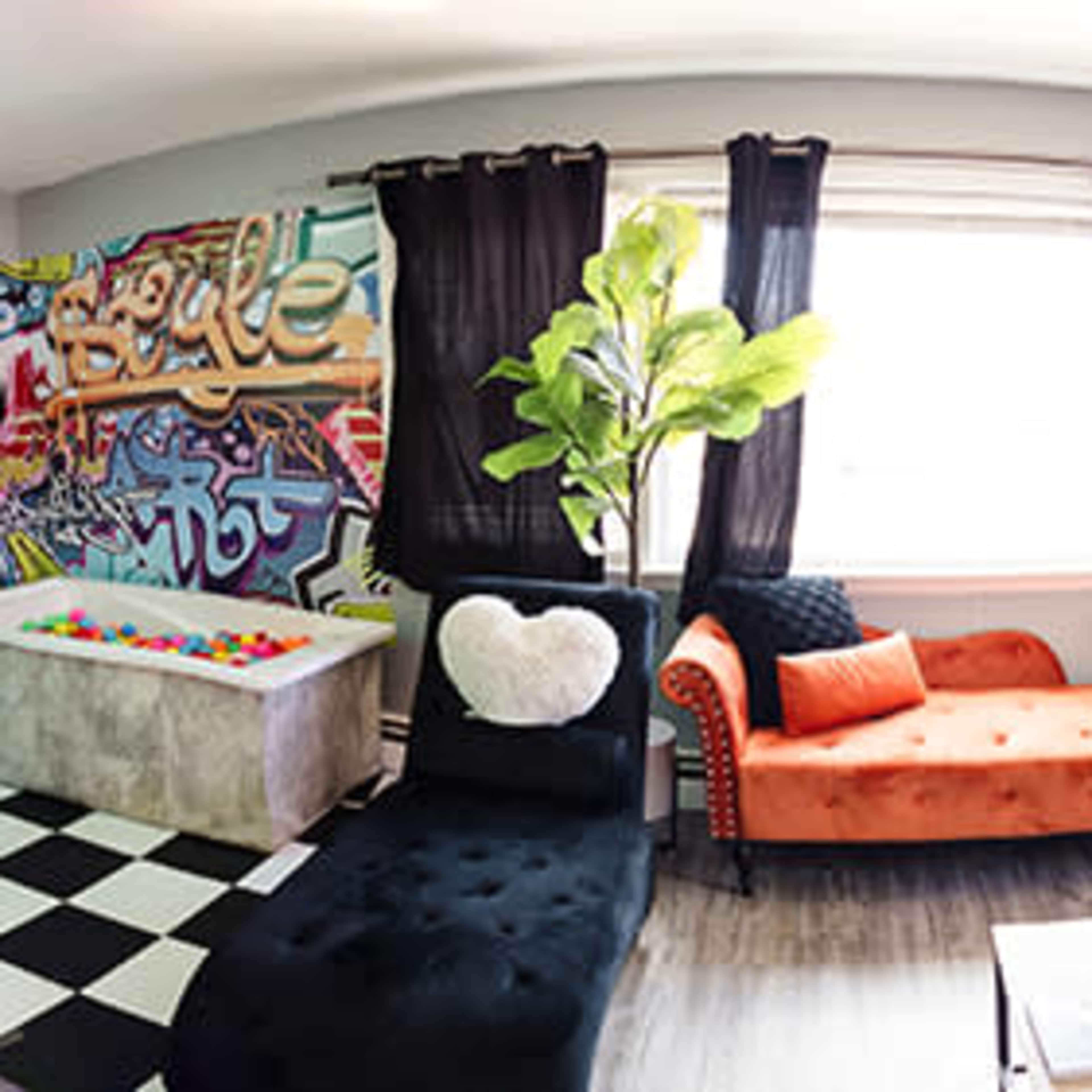 A panoramic view of a creatively designed room featuring a mix of colorful decor, furniture, and various wall patterns.