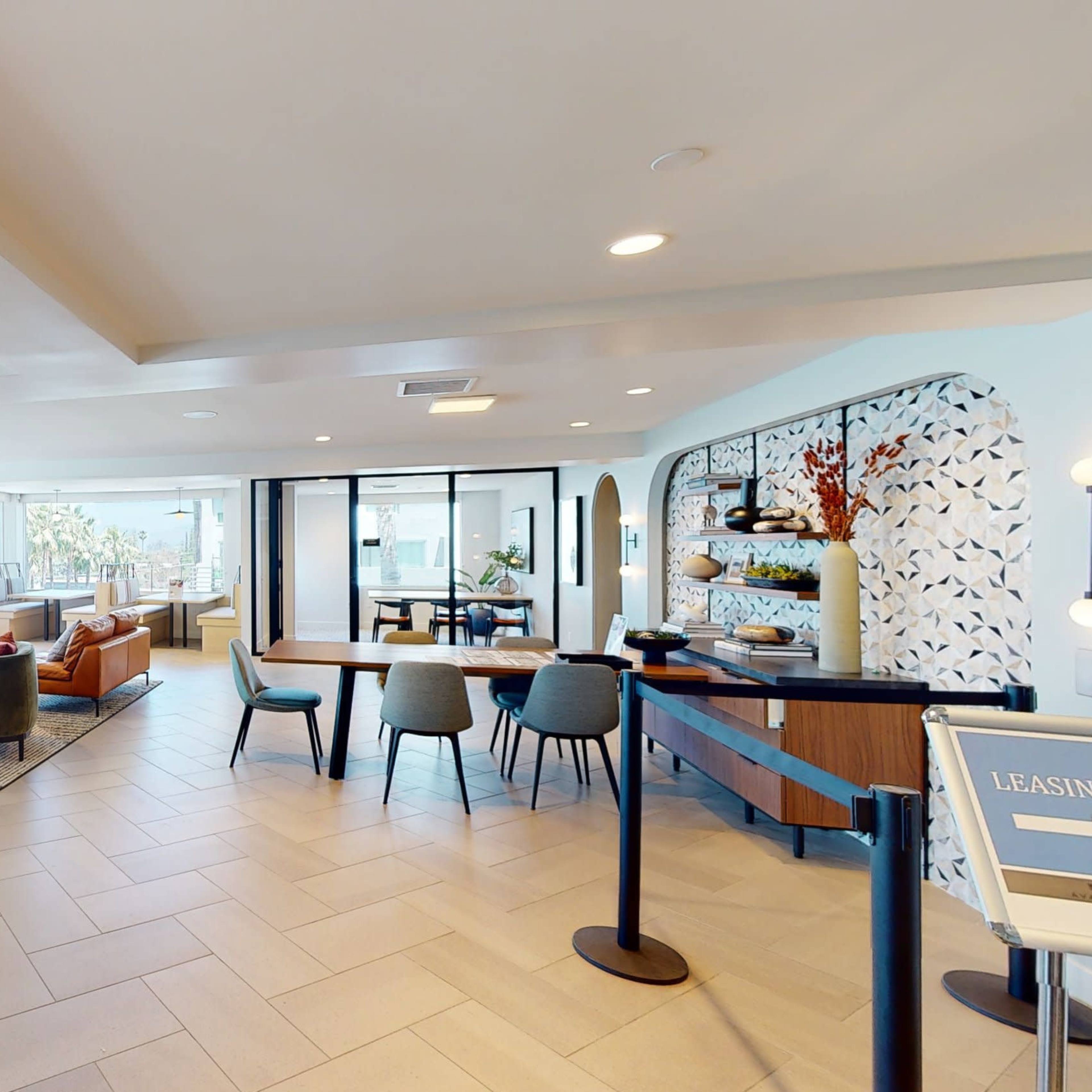 A modern lounge area featuring comfortable seating arrangements and natural light from large windows.