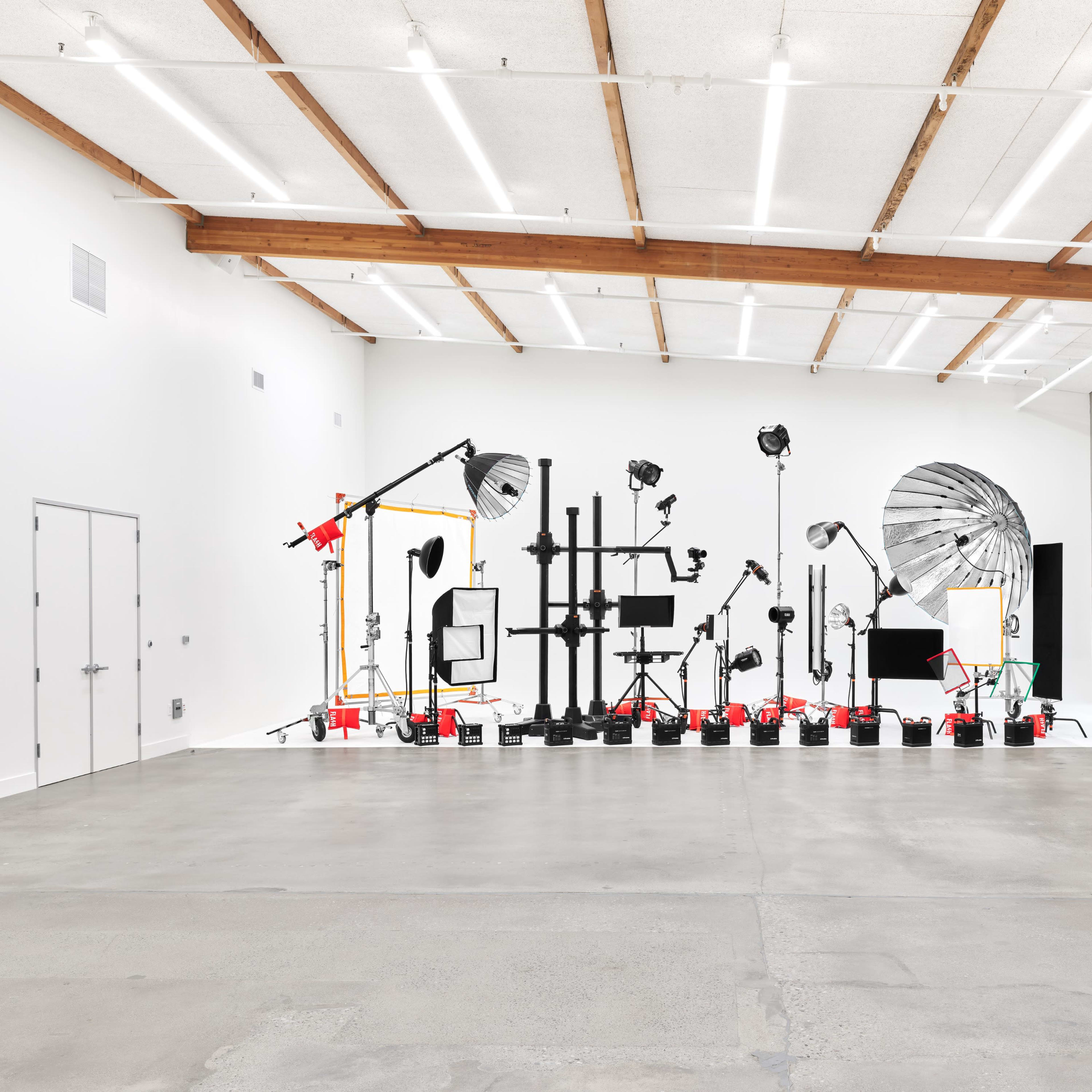 A photography studio with various lighting equipment and backdrops arranged against a white wall.