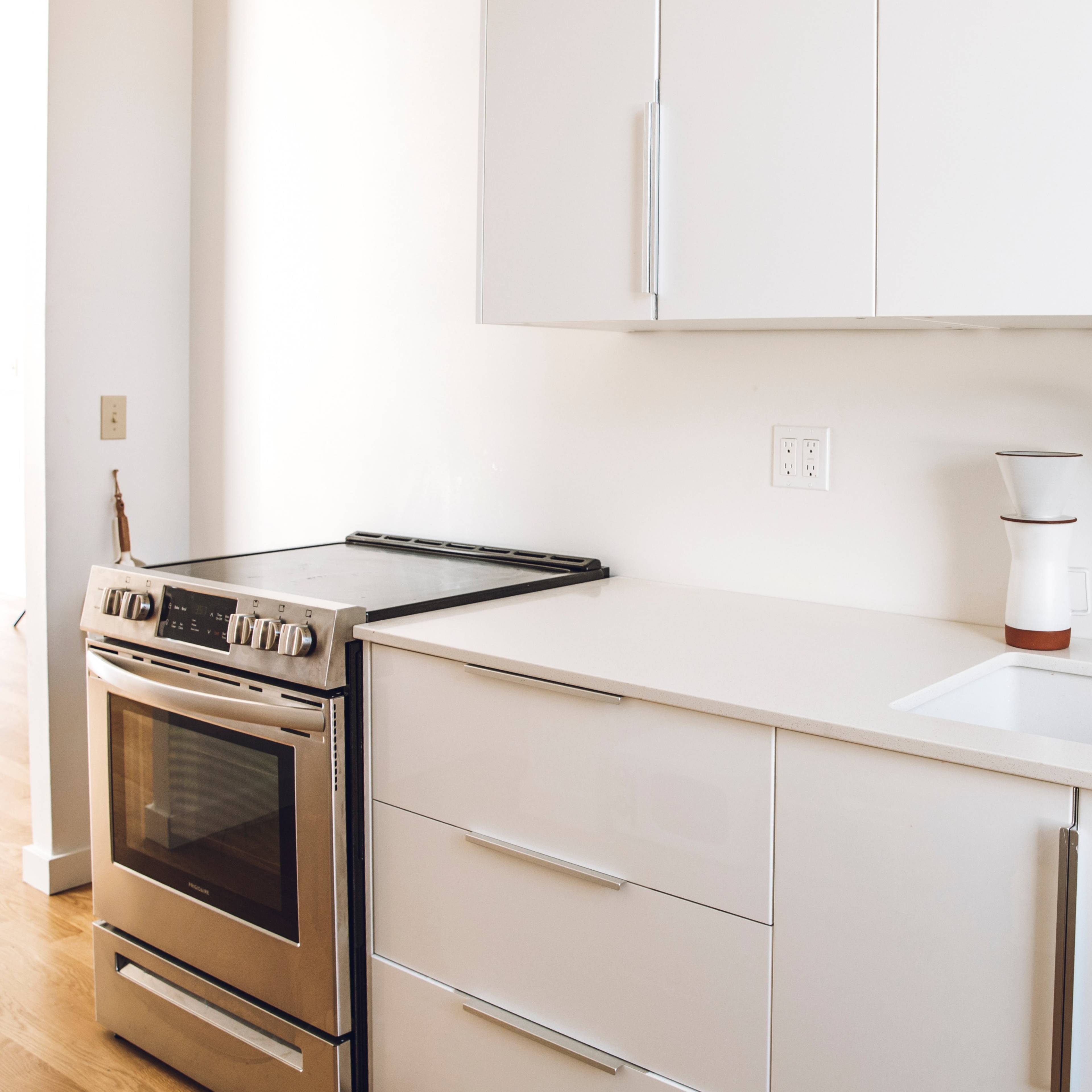 A modern kitchen featuring a stainless steel stove, a sleek sink, and minimalist cabinetry.