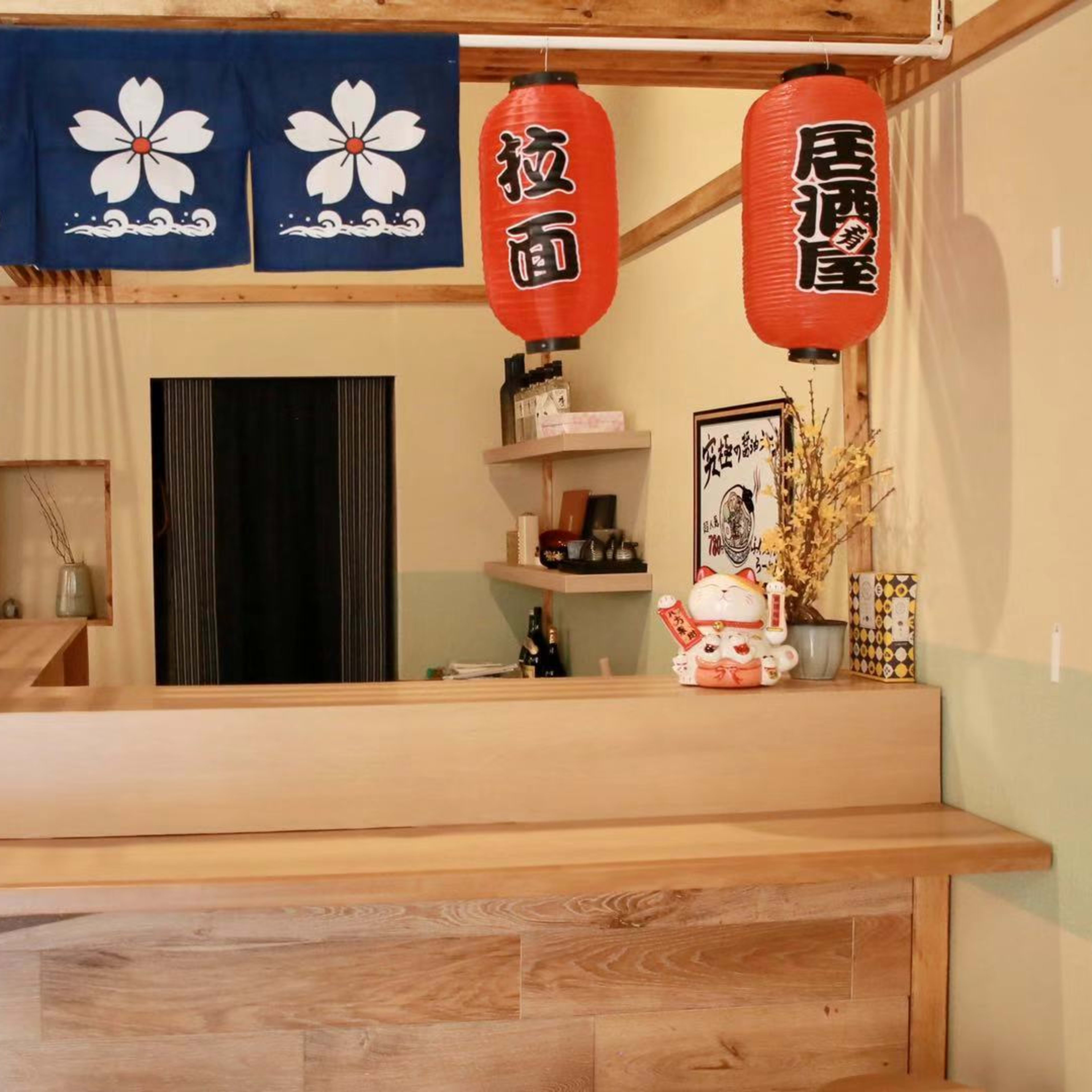 A wooden bar area with a dark curtain in the background, adorned with decorative lanterns and a traditional blue fabric banner.