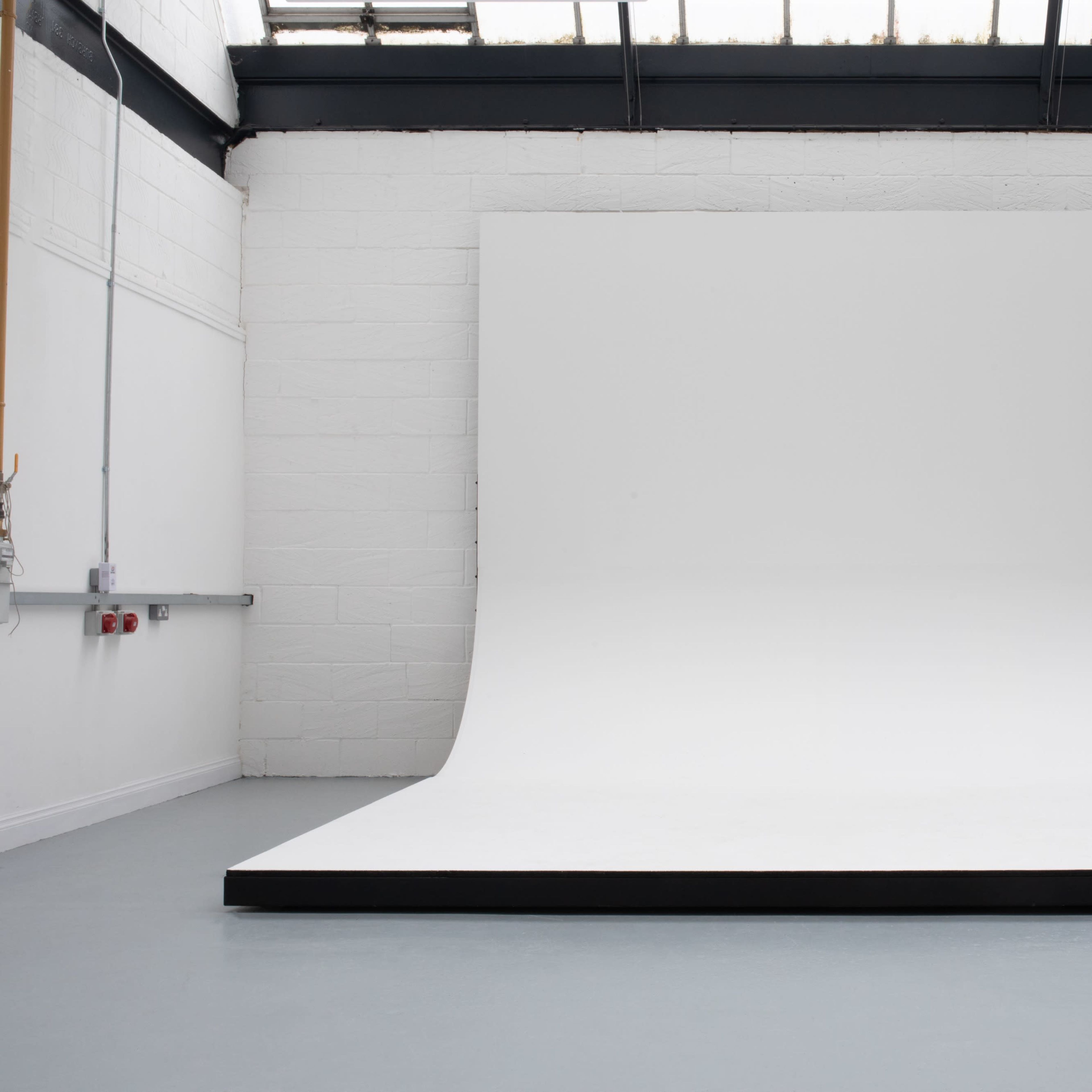 A large seamless white backdrop is set up on a raised platform in a well-lit studio space.
