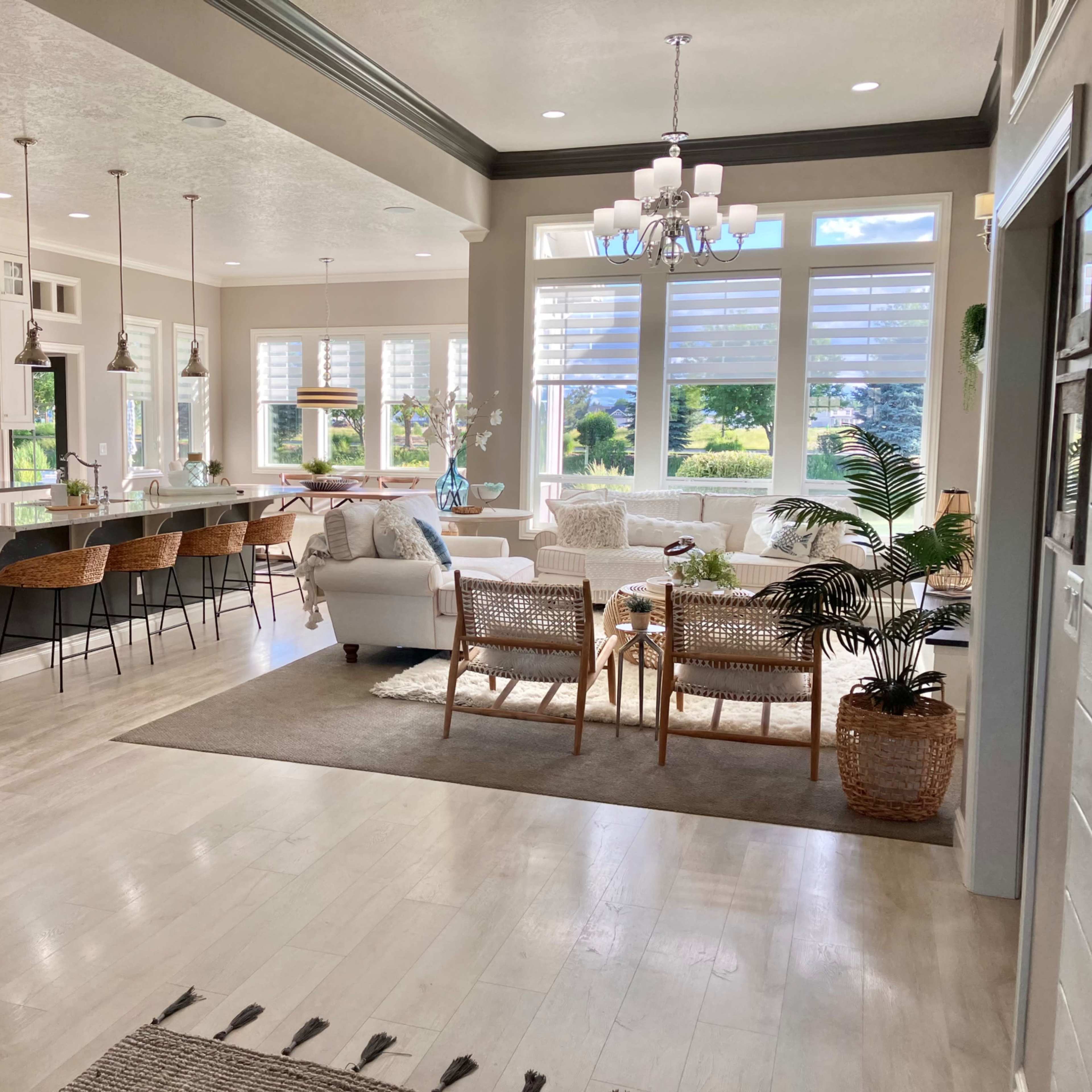 A bright, modern living space with a cozy seating area, large windows allowing natural light, and a kitchen with bar seating.