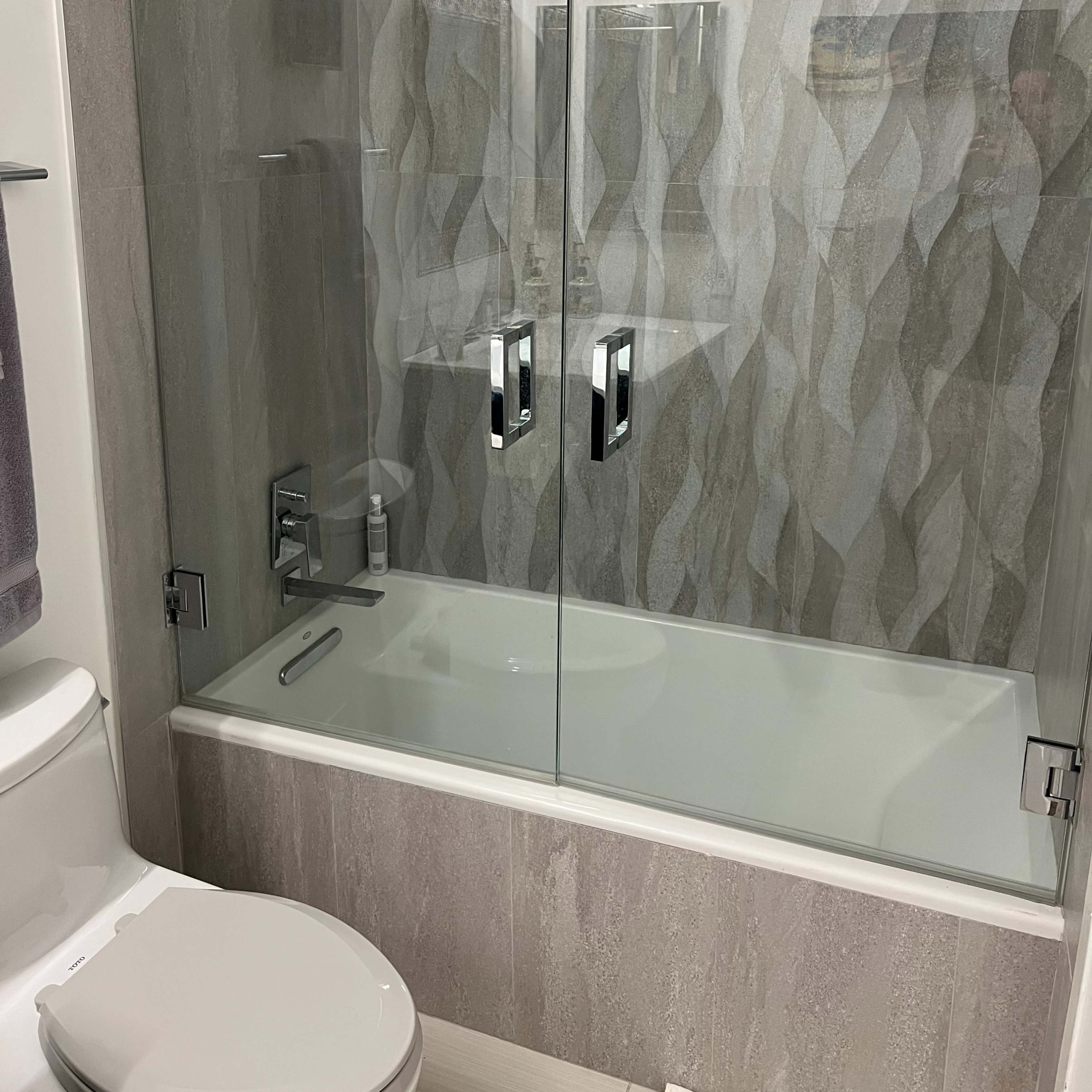 A modern bathroom with a glass shower enclosure, a bathtub, and a toilet.
