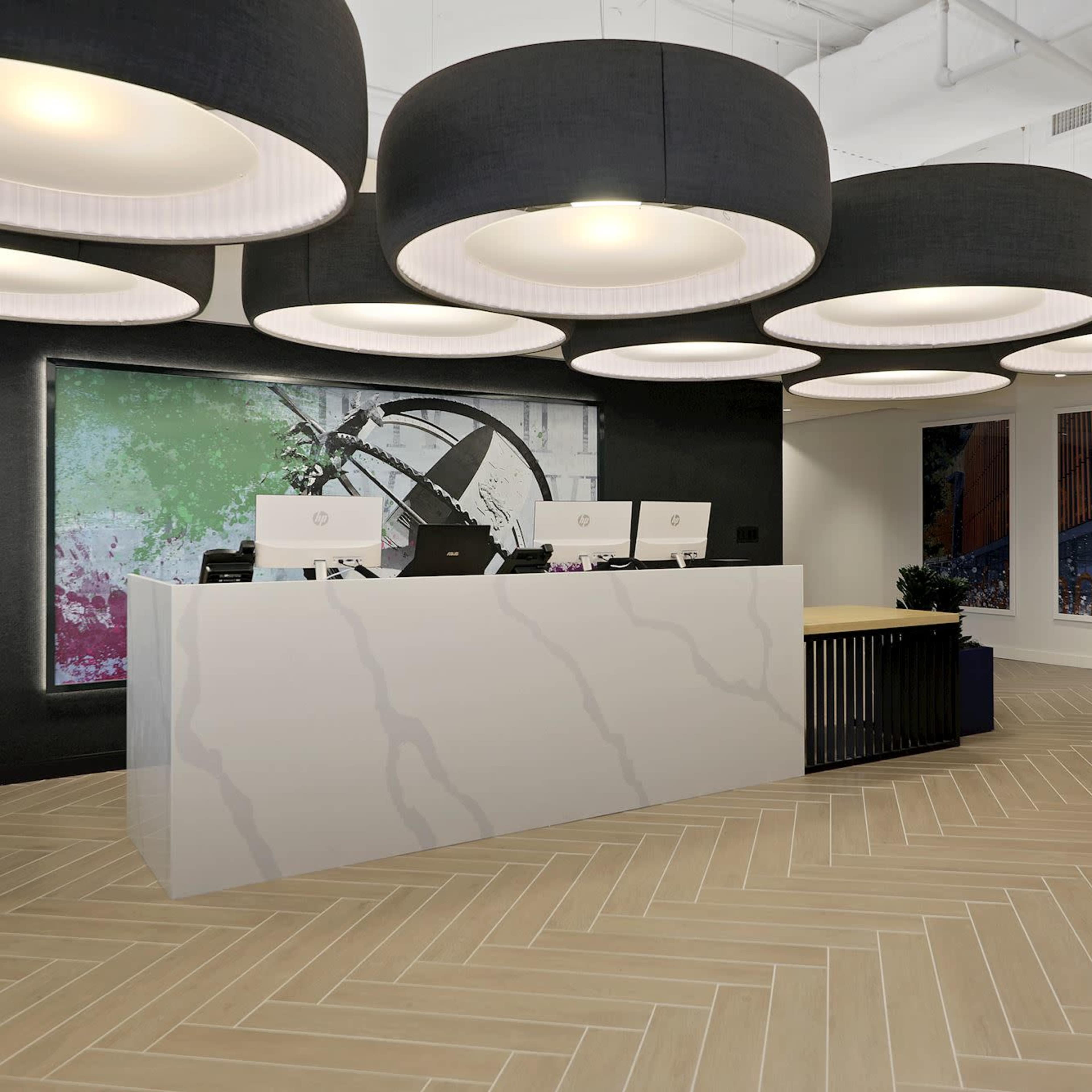 A modern reception area with a white marble counter, large round ceiling lights, and abstract artwork on the walls.