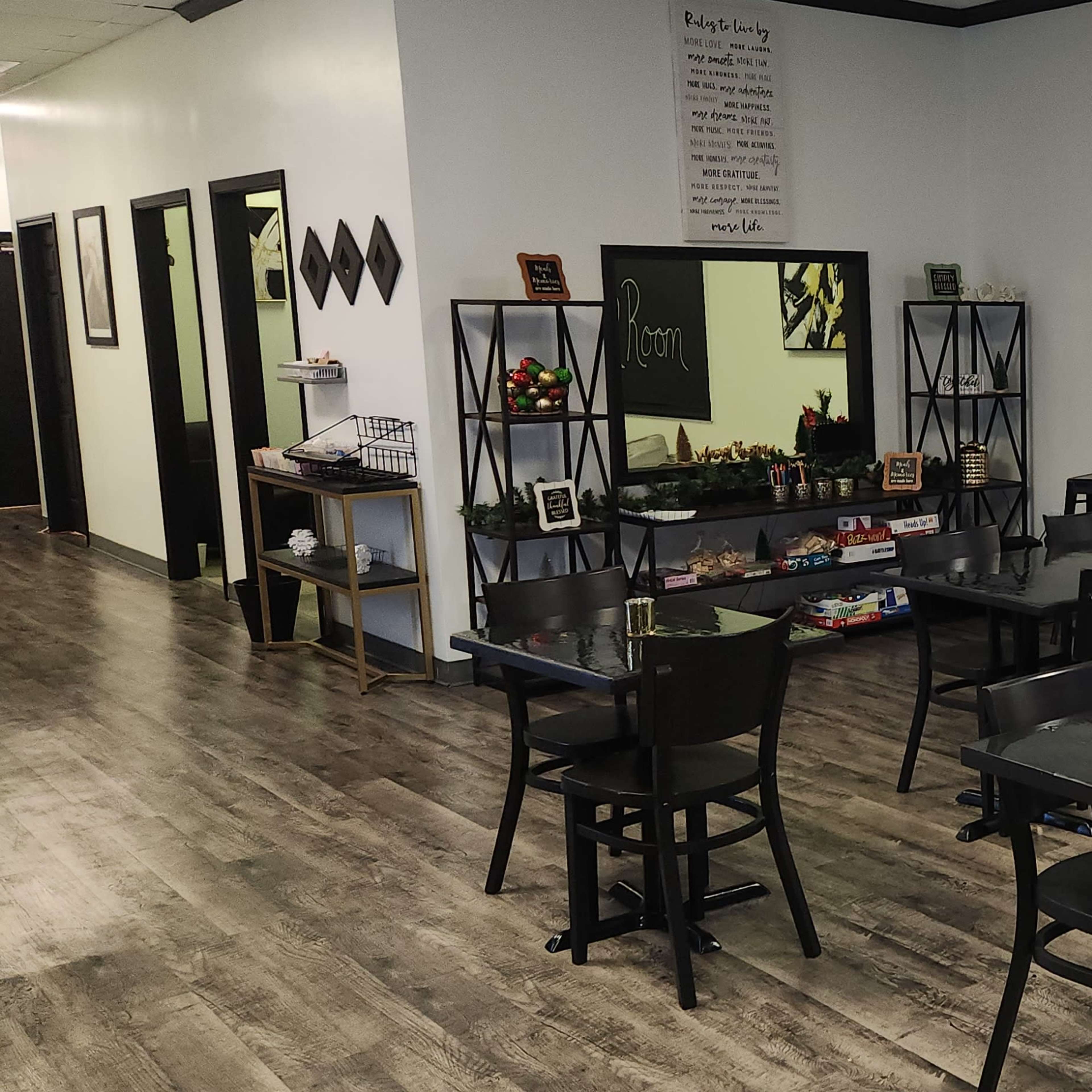 A dining area with several black tables and chairs, accompanied by tall bar stools and a wall-mounted television.