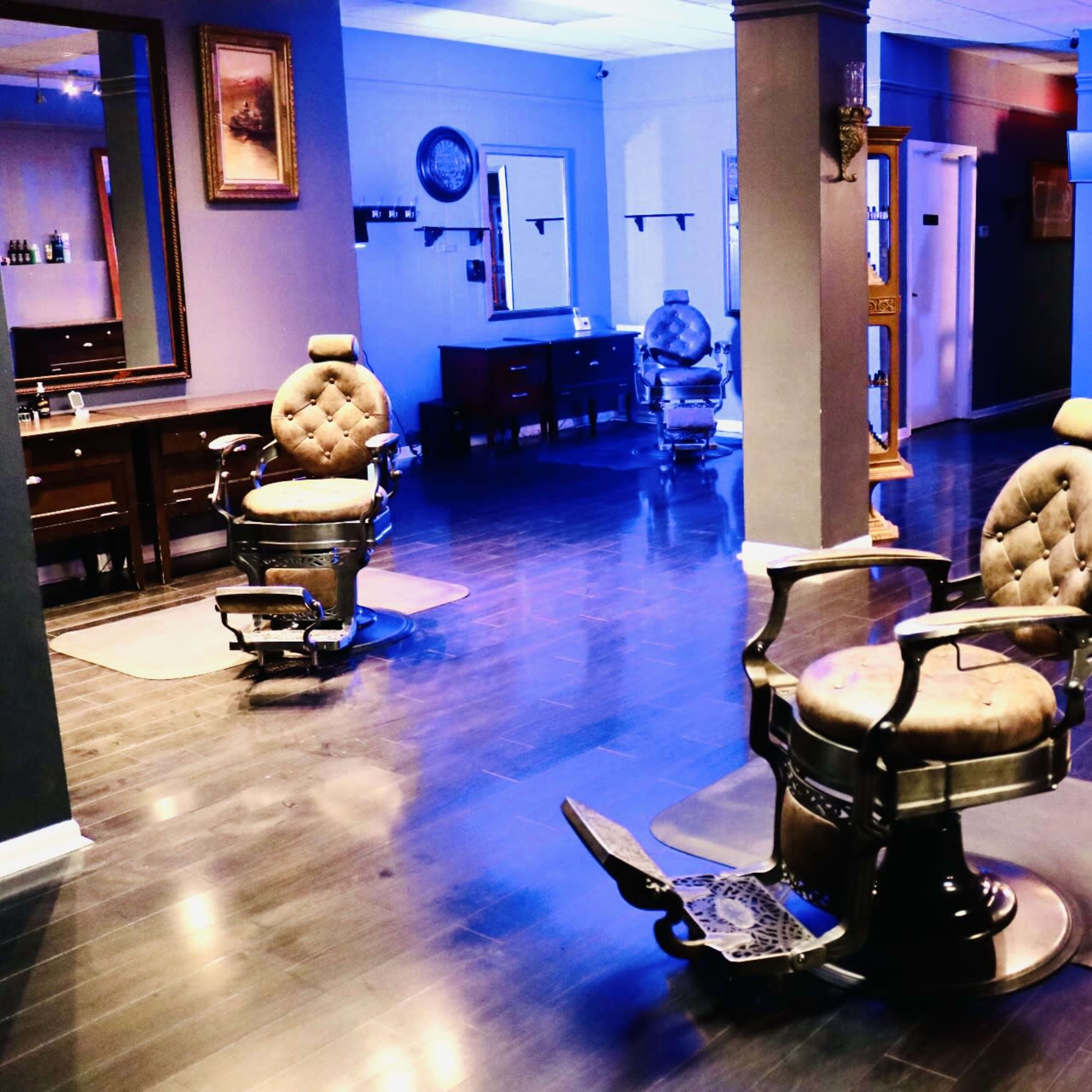 A spacious barber shop interior with several vintage barber chairs and grooming stations in a well-lit environment.
