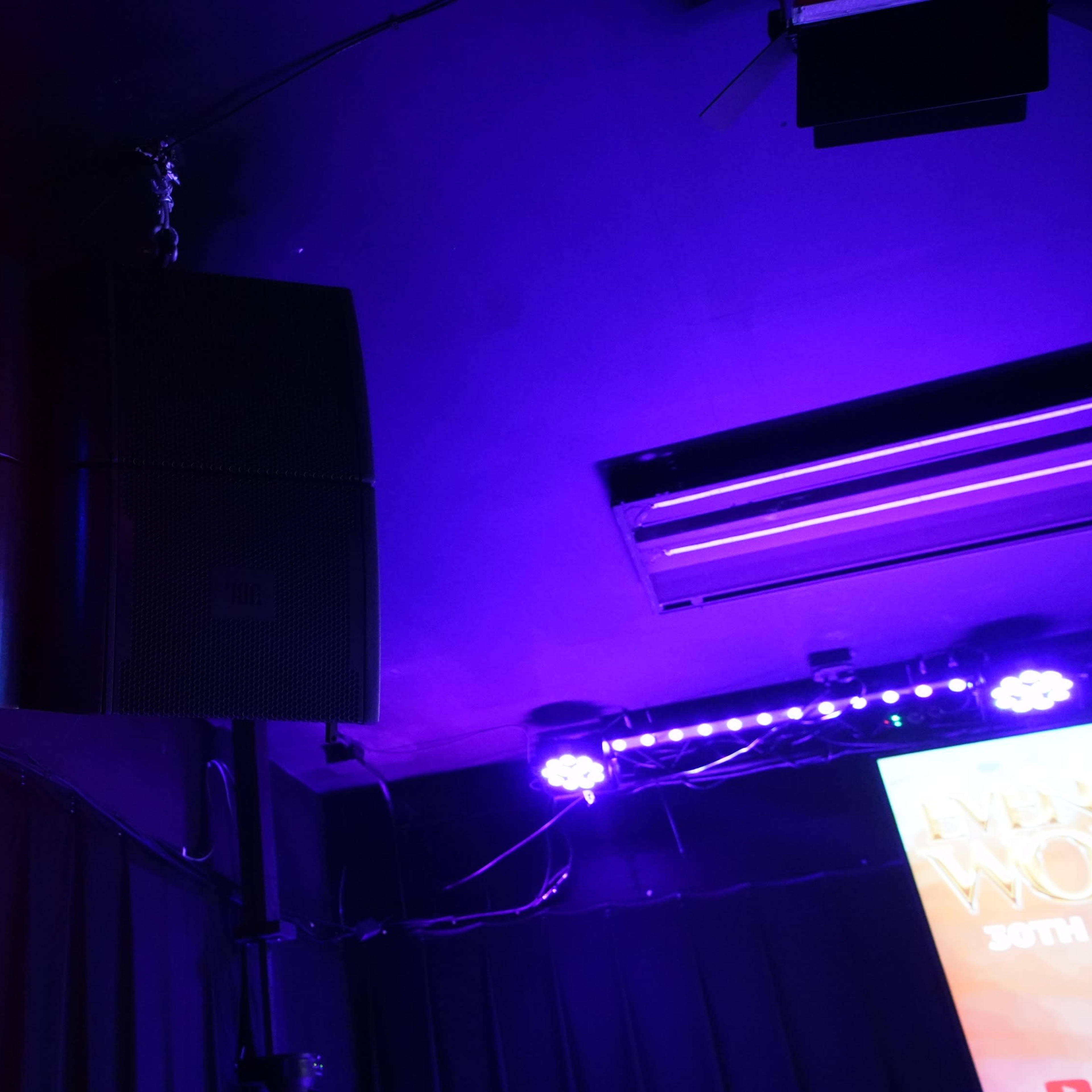 A suspended speaker system with colorful stage lights illuminating the surrounding area.