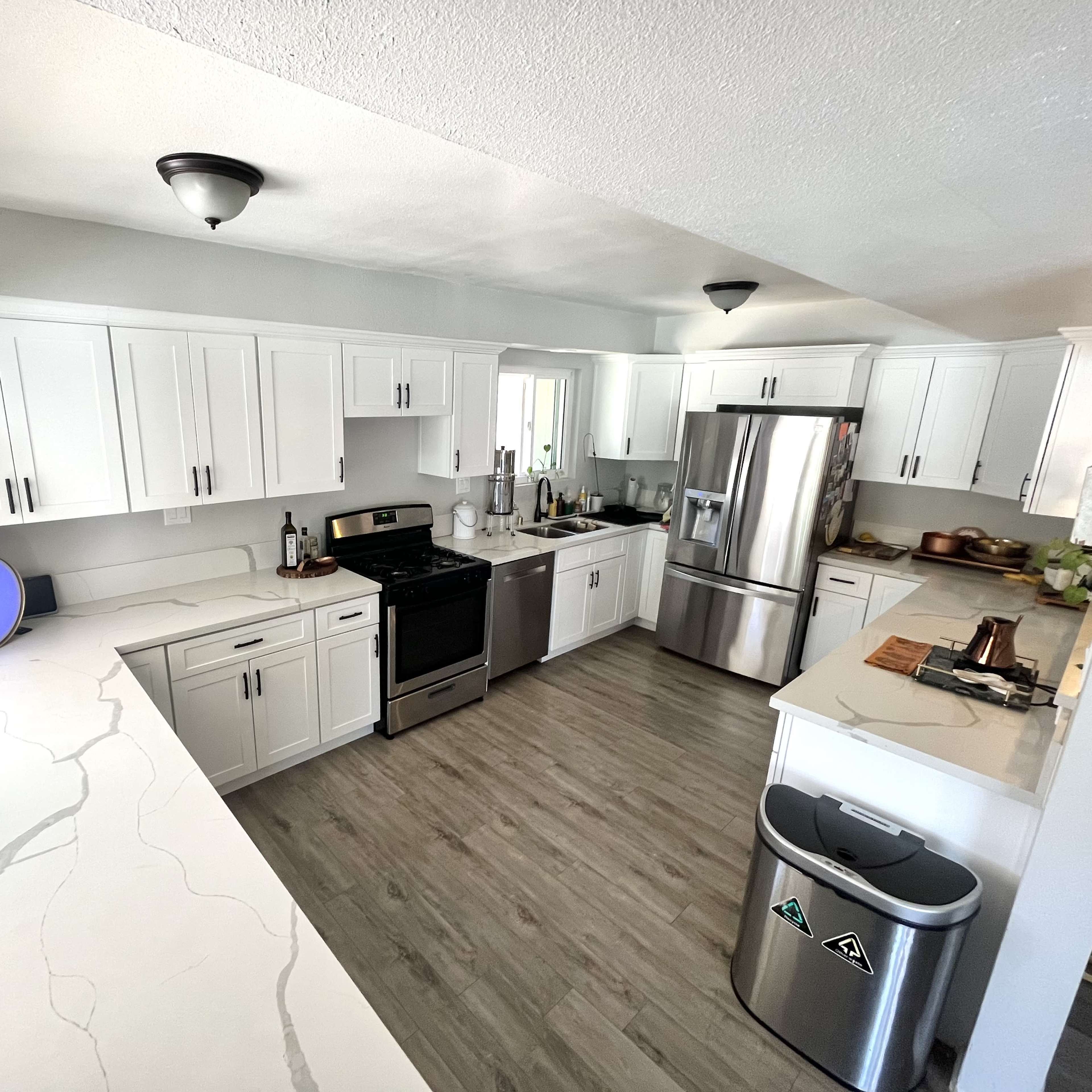 The kitchen features white cabinets, a stainless steel refrigerator, and light-colored countertops with a spacious layout.