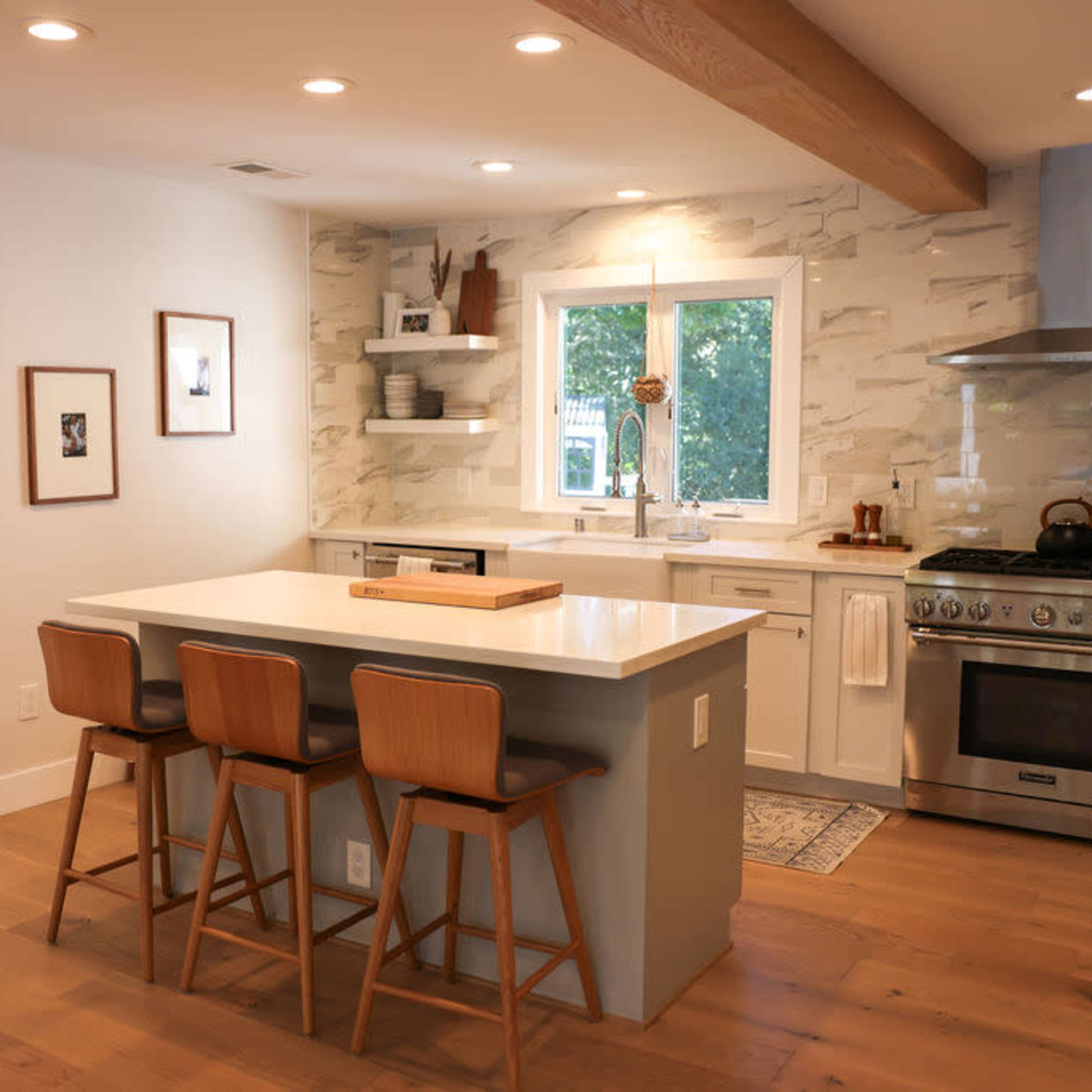 A modern kitchen features a large island with three wooden stools, a stainless steel stove, and a window that overlooks a well-lit living area.
