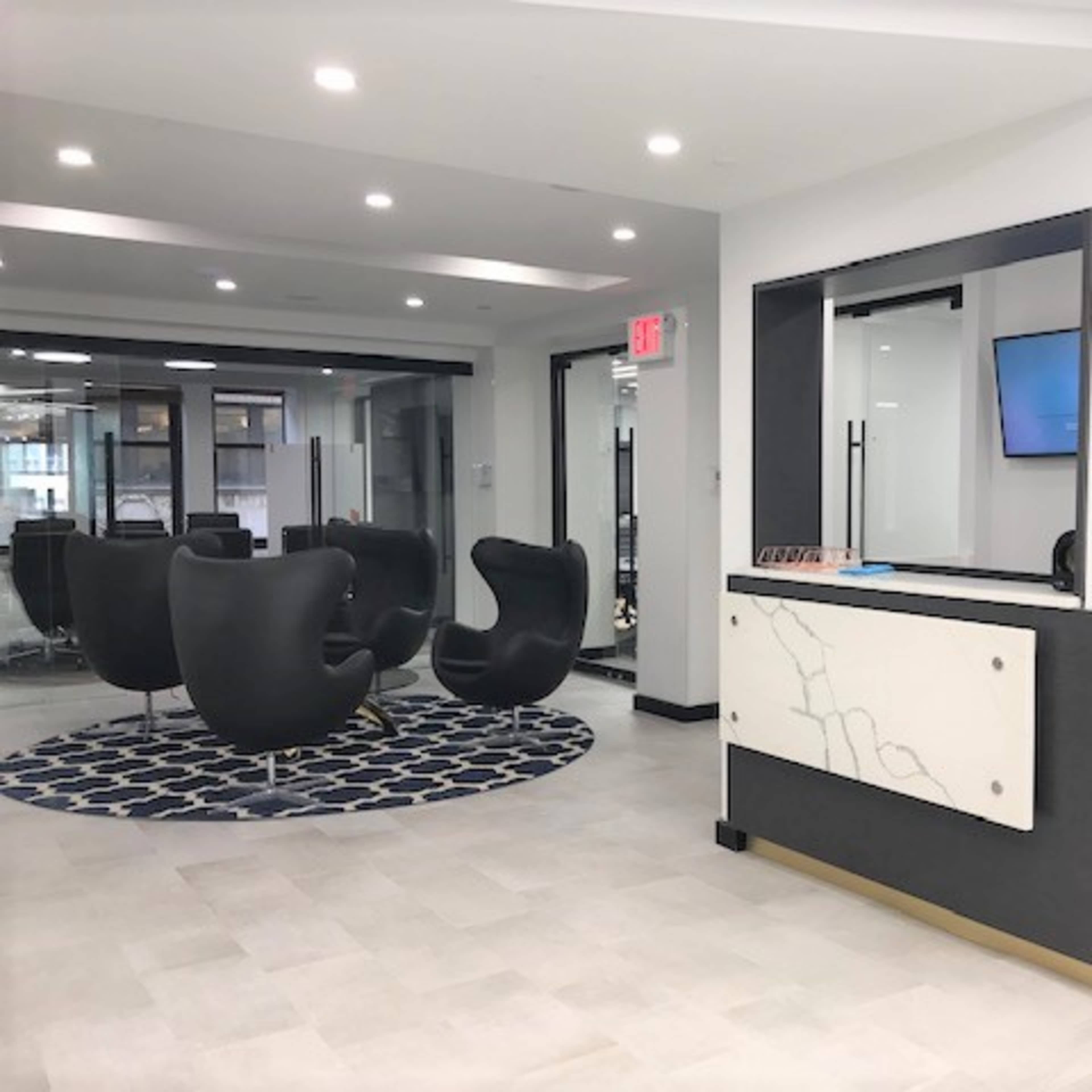A modern reception area with stylish black chairs, a sleek front desk, and decorative flowers.
