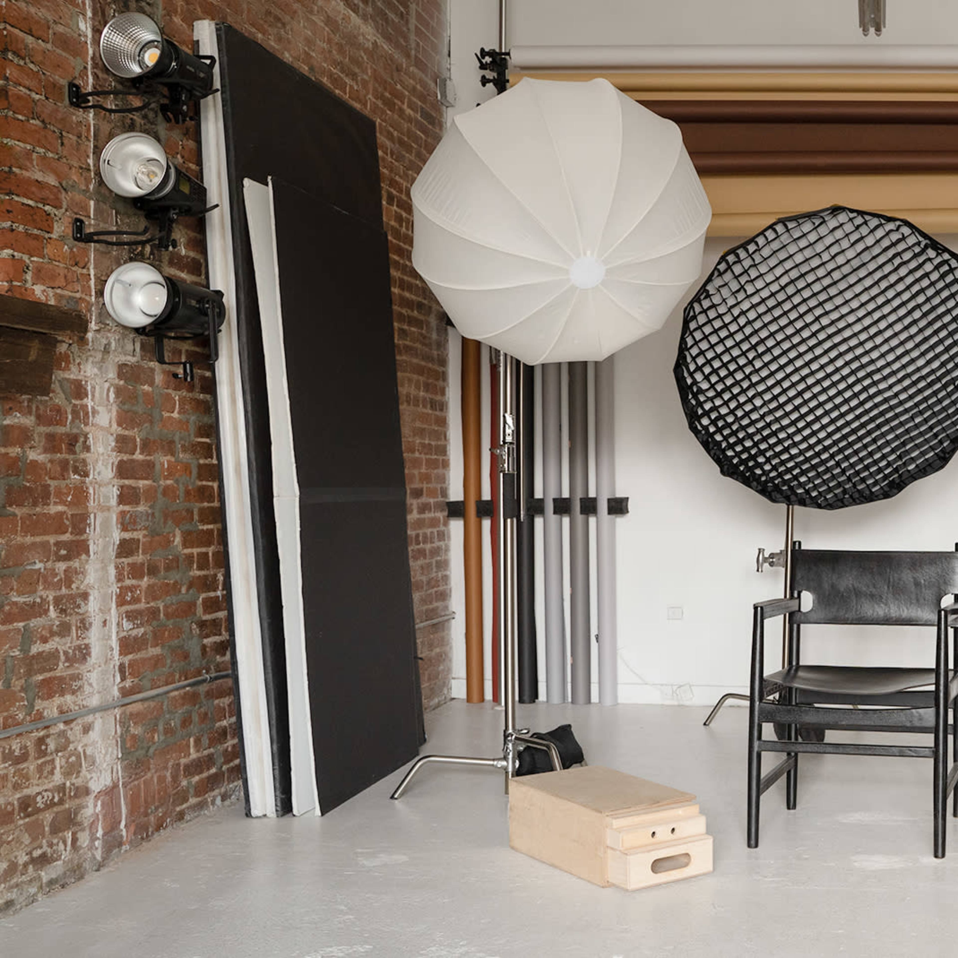 A photography studio setup with various backdrops, lighting equipment, and a chair.