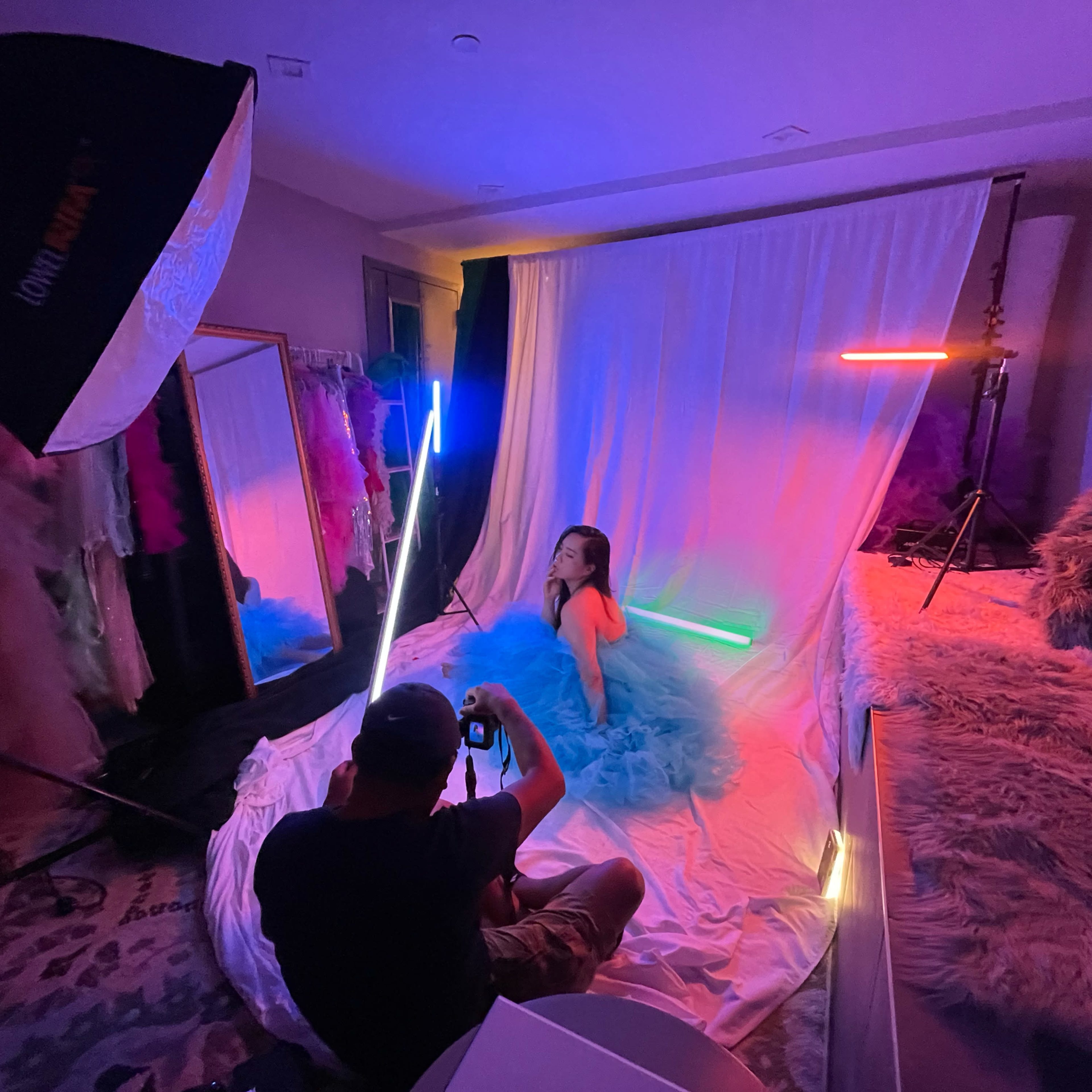 A model in a blue tutu poses for a photographer in a colorful studio with various lighting setups.
