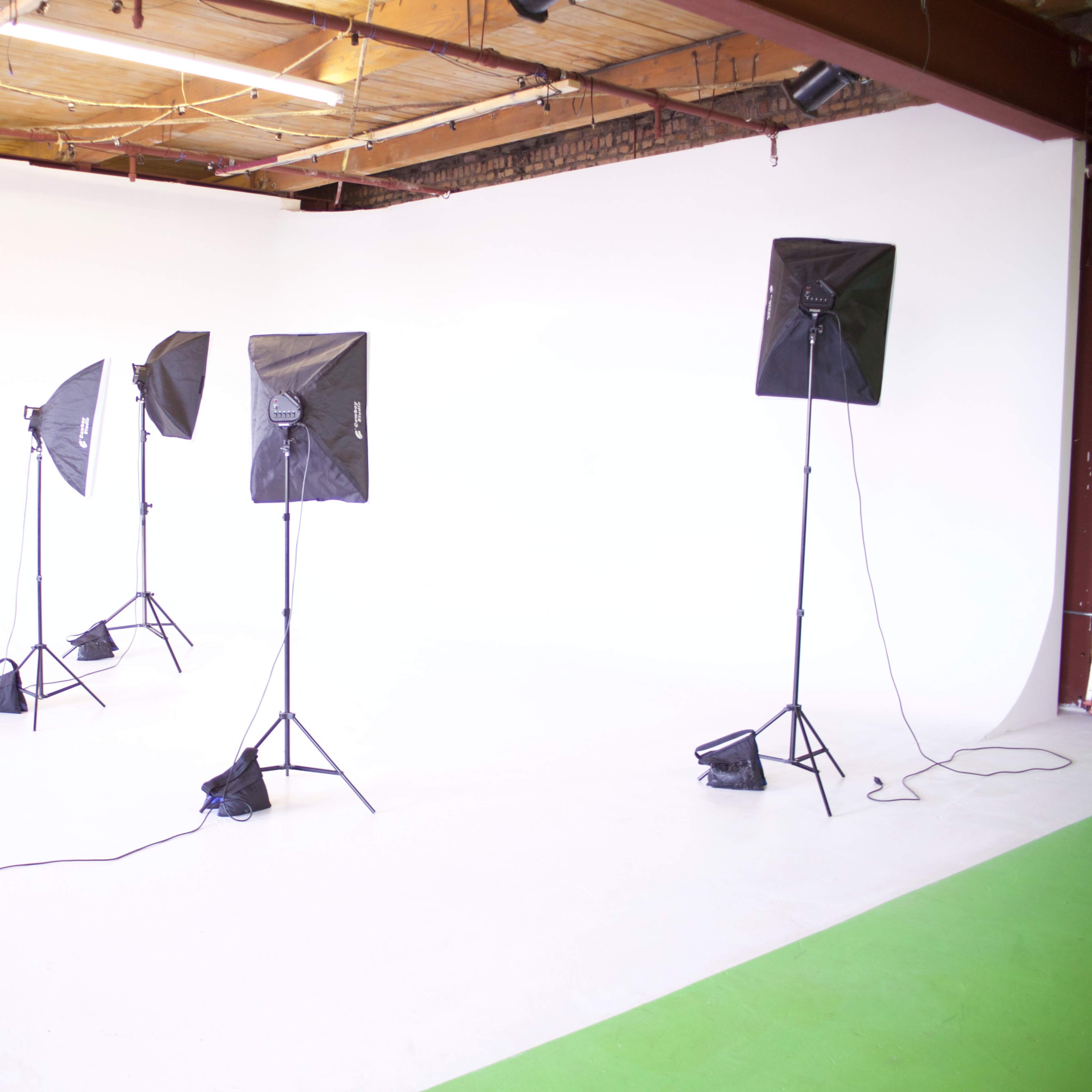 A photography studio with four softbox lights positioned around a blank white backdrop.