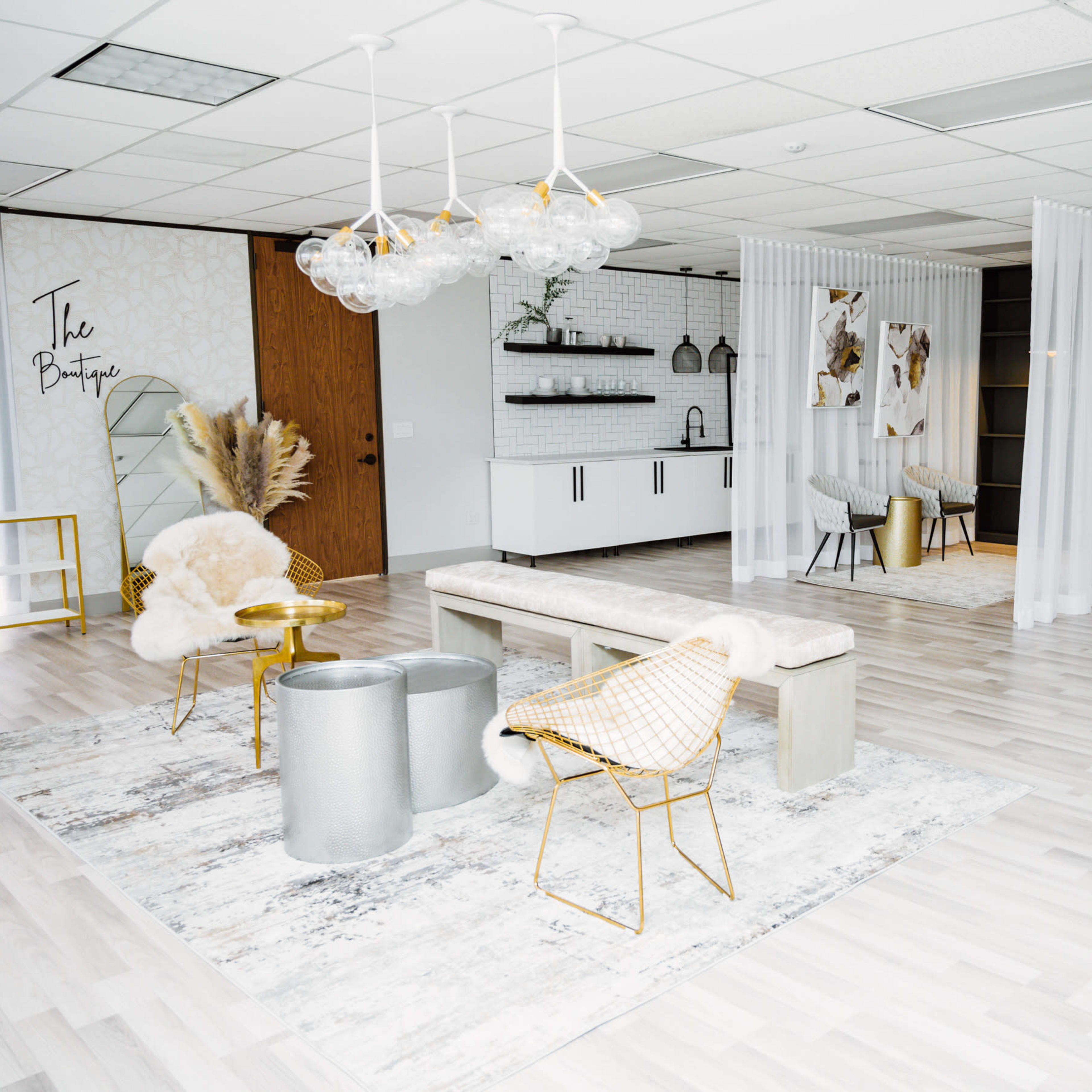 A modern, stylish interior space with light wooden flooring, a seating area featuring a bench and decorative chairs, and partitioned sections for different uses.